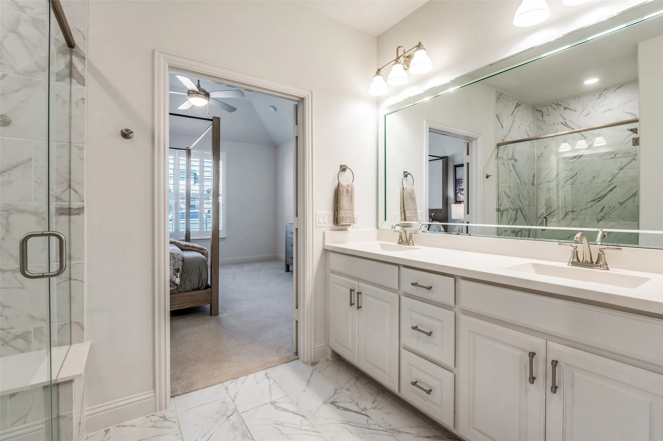 Luxurious primary bath featuring dual vanities, quartz countertops, and a large mirror with elegant lighting. The bright, open layout offers both style and functionality.