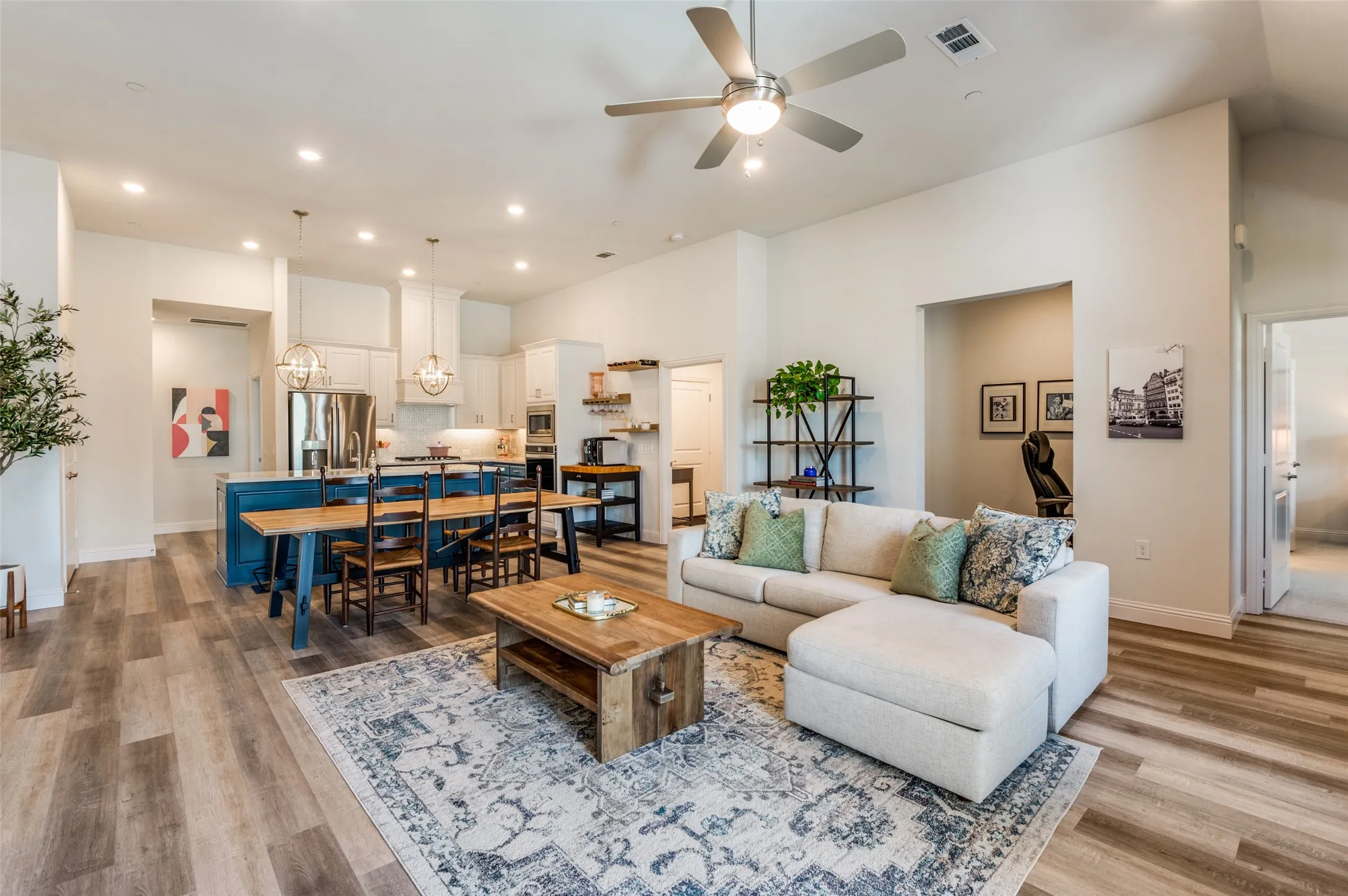Gorgeous kitchen overlooking the living area, featuring a large island with seating, stylish pendant lighting, and stainless steel appliances. Perfect for both casual meals and entertaining guests.