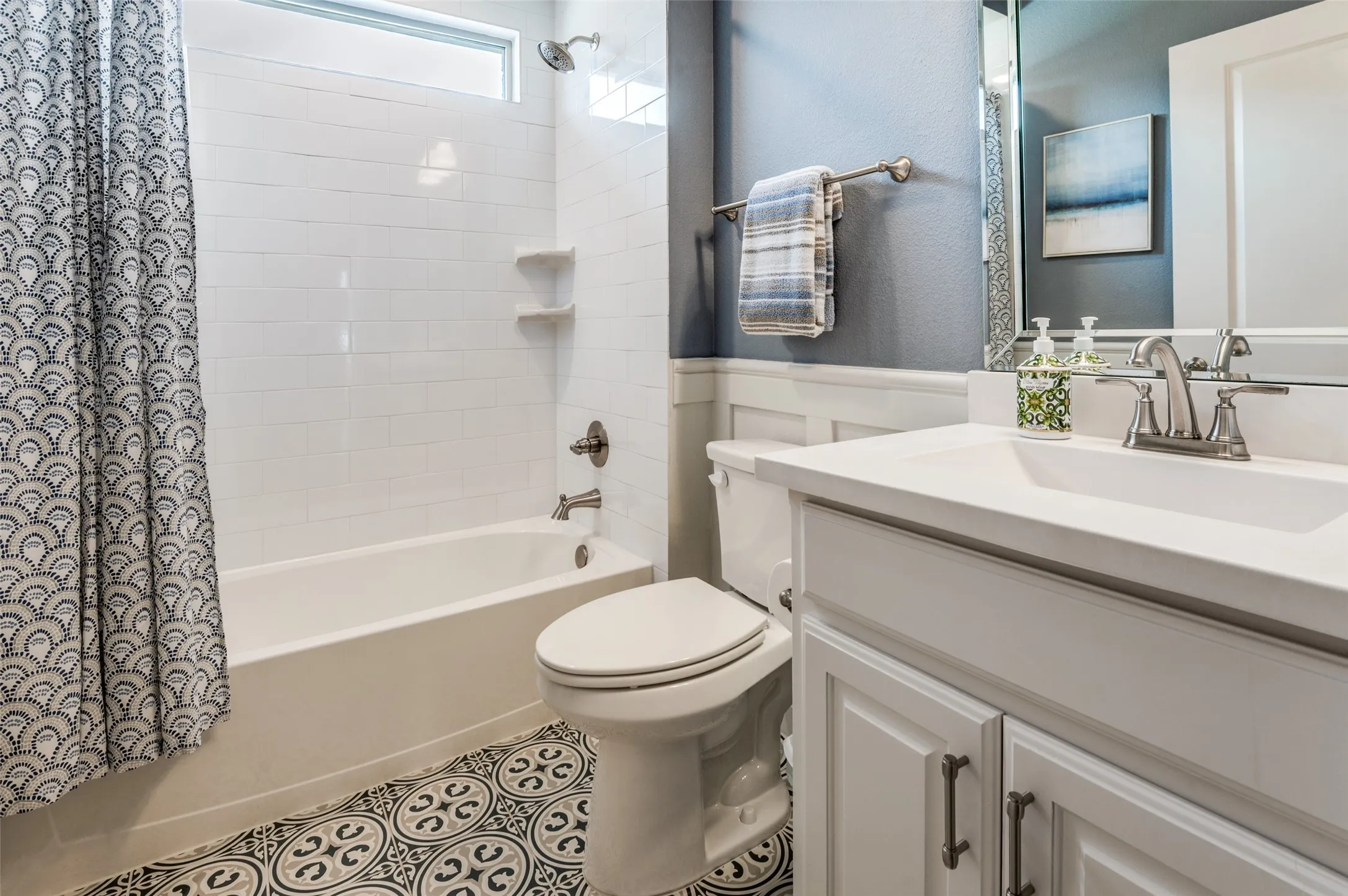 Stylish full bathroom featuring a tub and shower combo, modern tile flooring, and a bright vanity with plenty of storage.