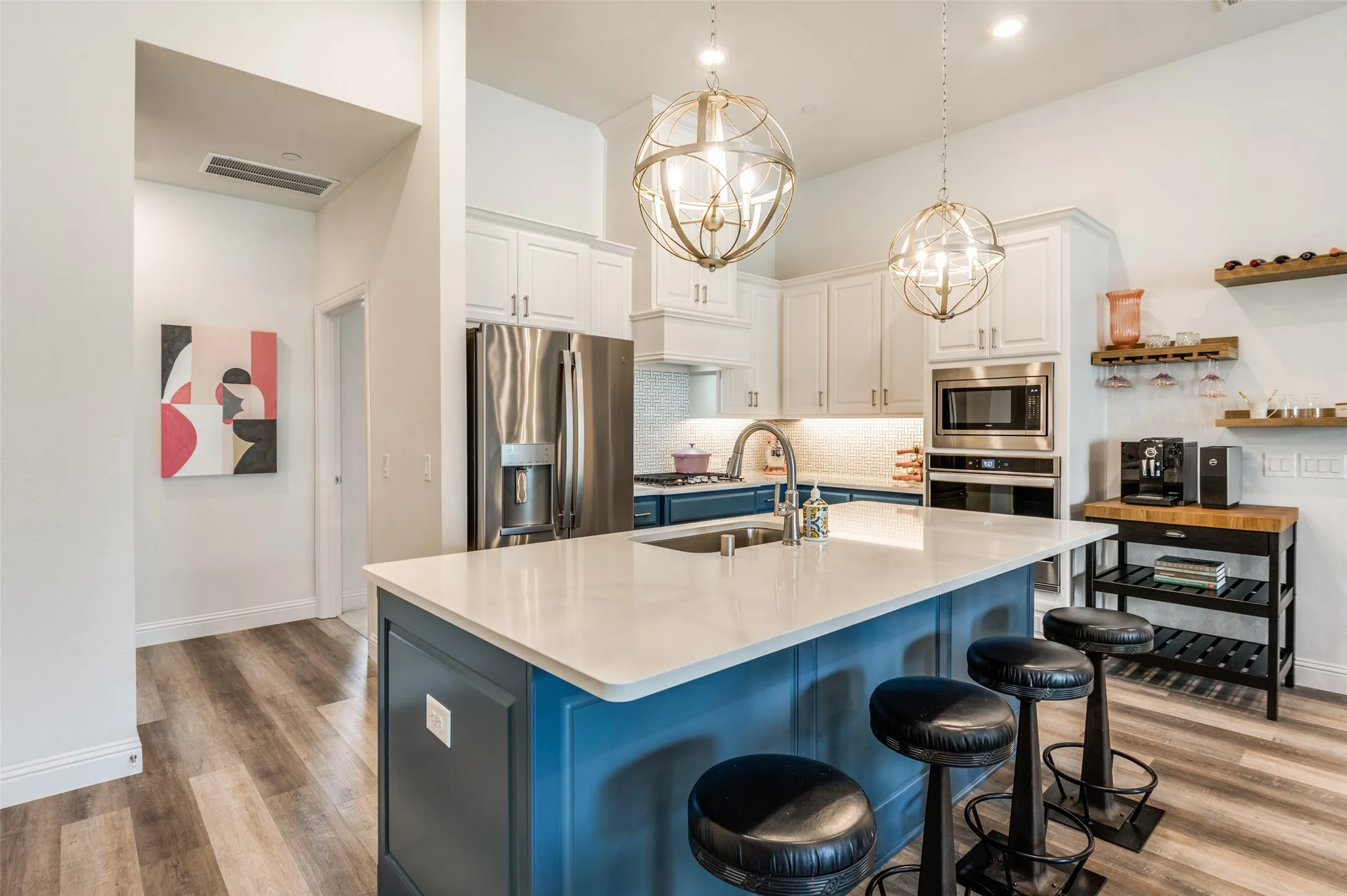 Beautiful chef’s kitchen featuring a large island with seating, quartz countertops, stainless steel appliances, and stylish pendant lighting.