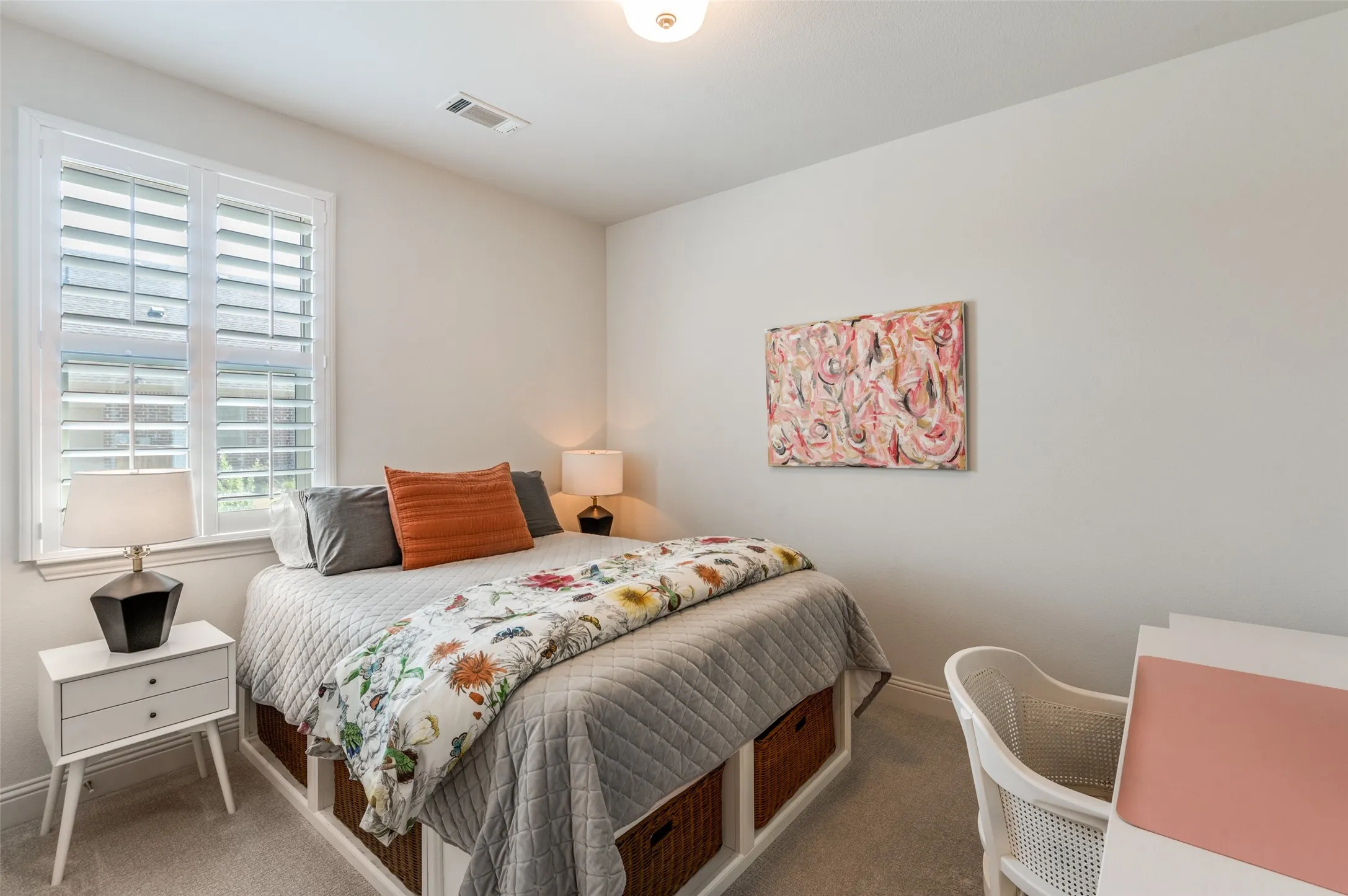 Comfortable secondary bedroom with soft carpeting, large window with plantation shutters, and space for a desk or study area.