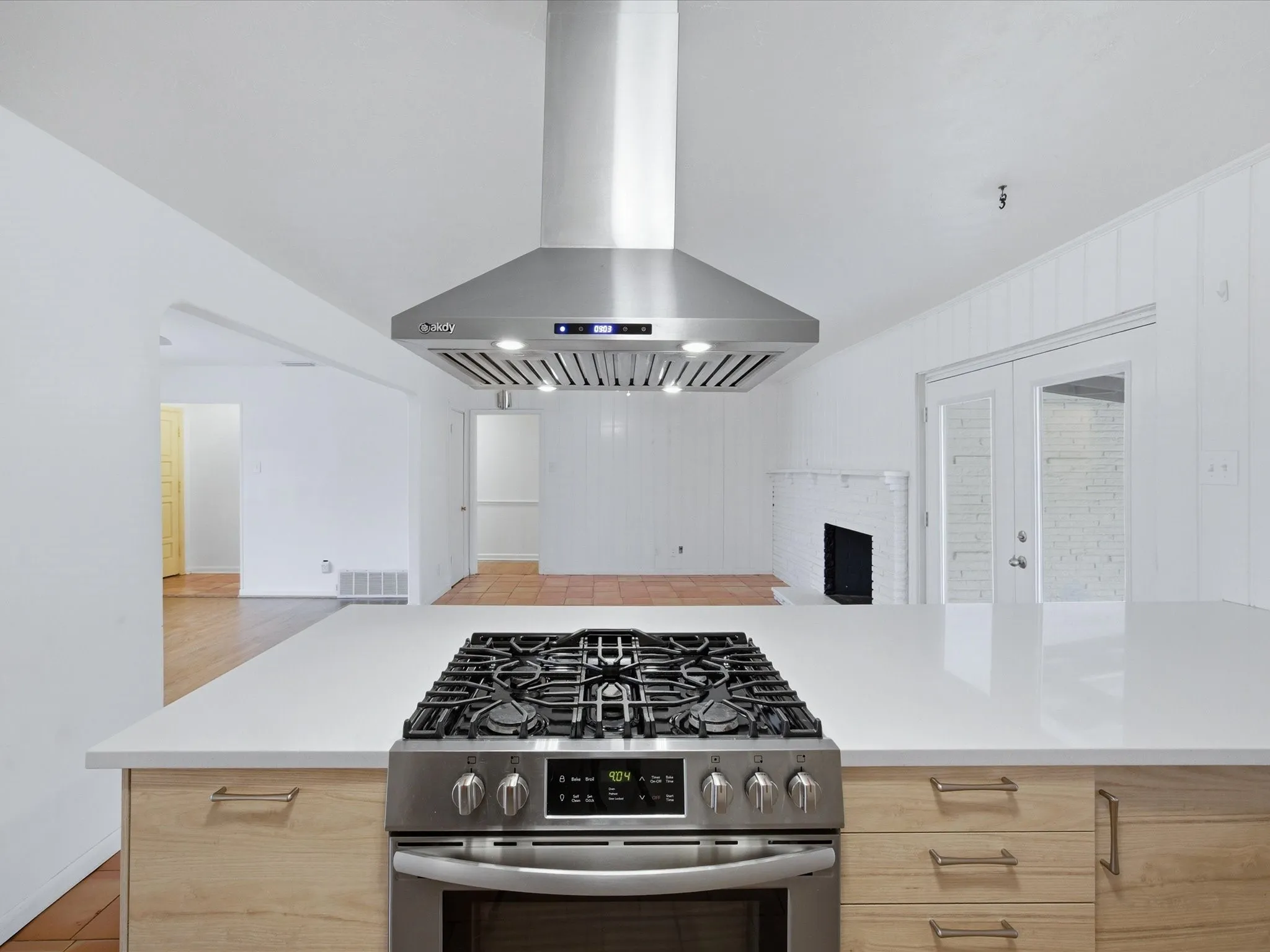 Kitchen with open floor plan, gas range, light wood finish cabinets, and a fireplace