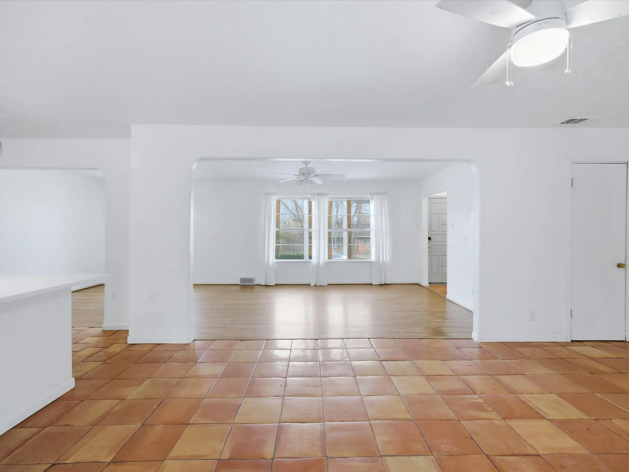 Unfurnished living room featuring ceiling fan, wooden walls, french doors, and a brick fireplace