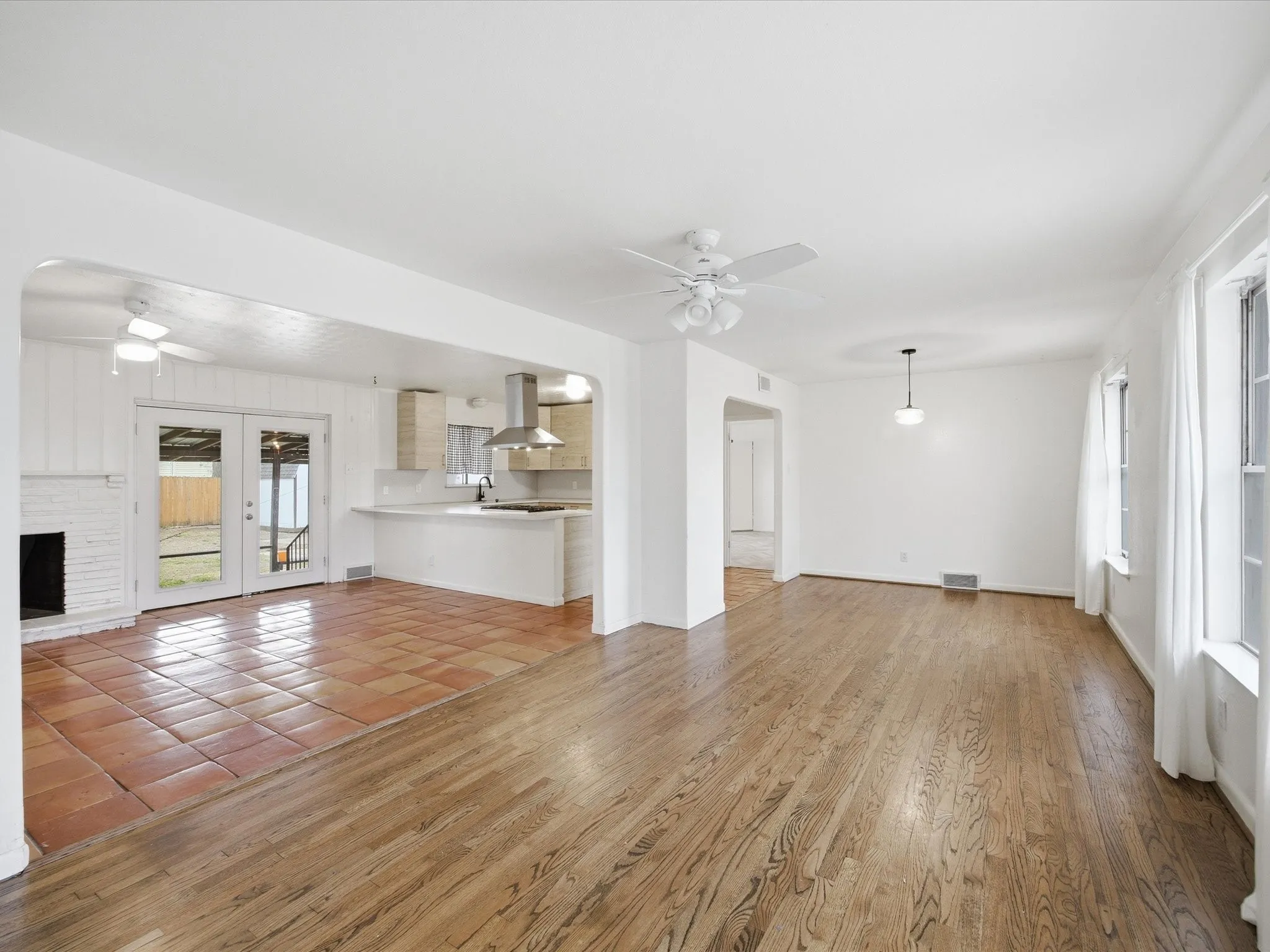 Unfurnished living room featuring ceiling fan, light wood-style floors, and arched walkways