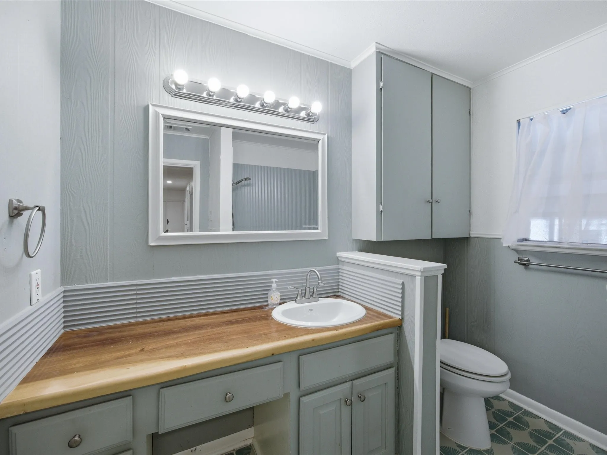 Bathroom with vanity, a decorative wall, ornamental molding, and wood walls