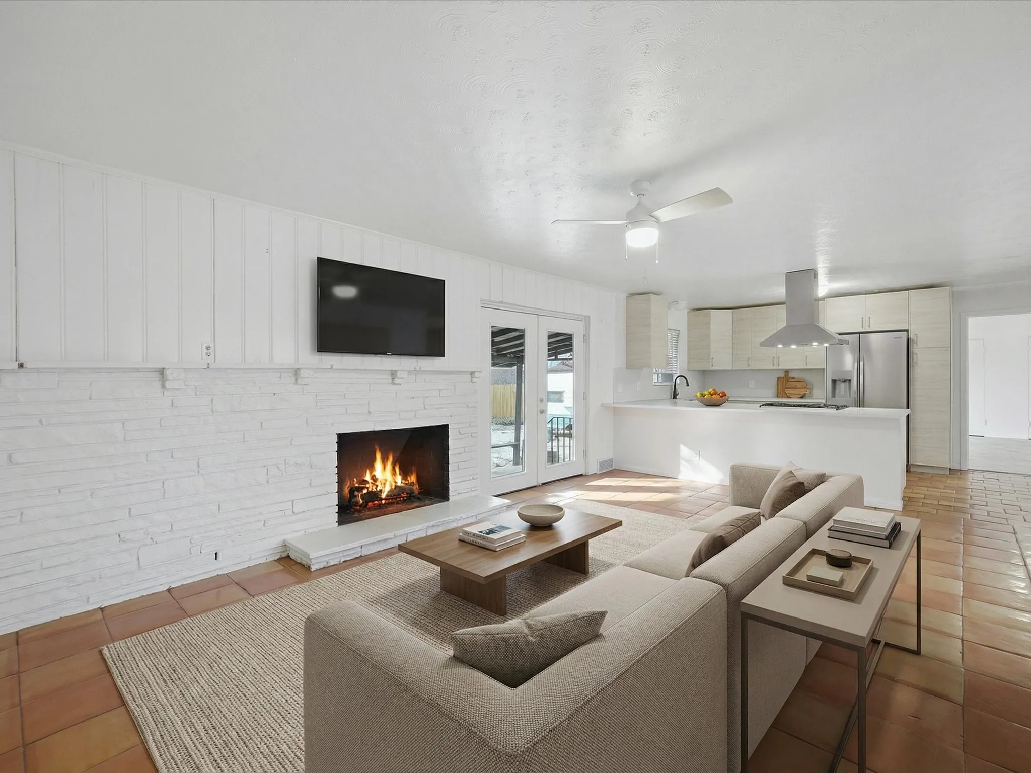 Living area with a fireplace, light tile patterned flooring, and a ceiling fan