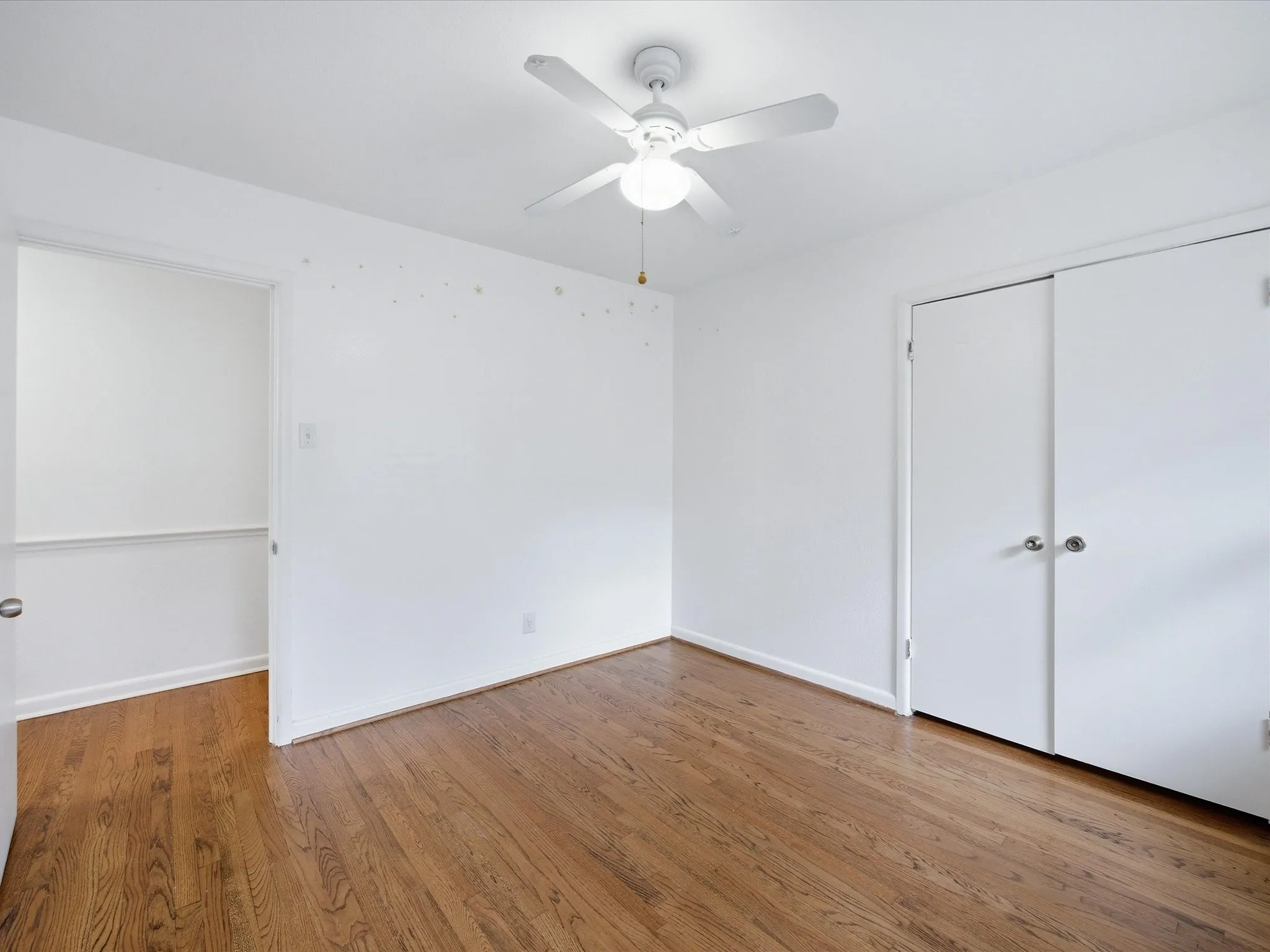 Unfurnished bedroom featuring dark wood-style flooring, a ceiling fan, and a closet