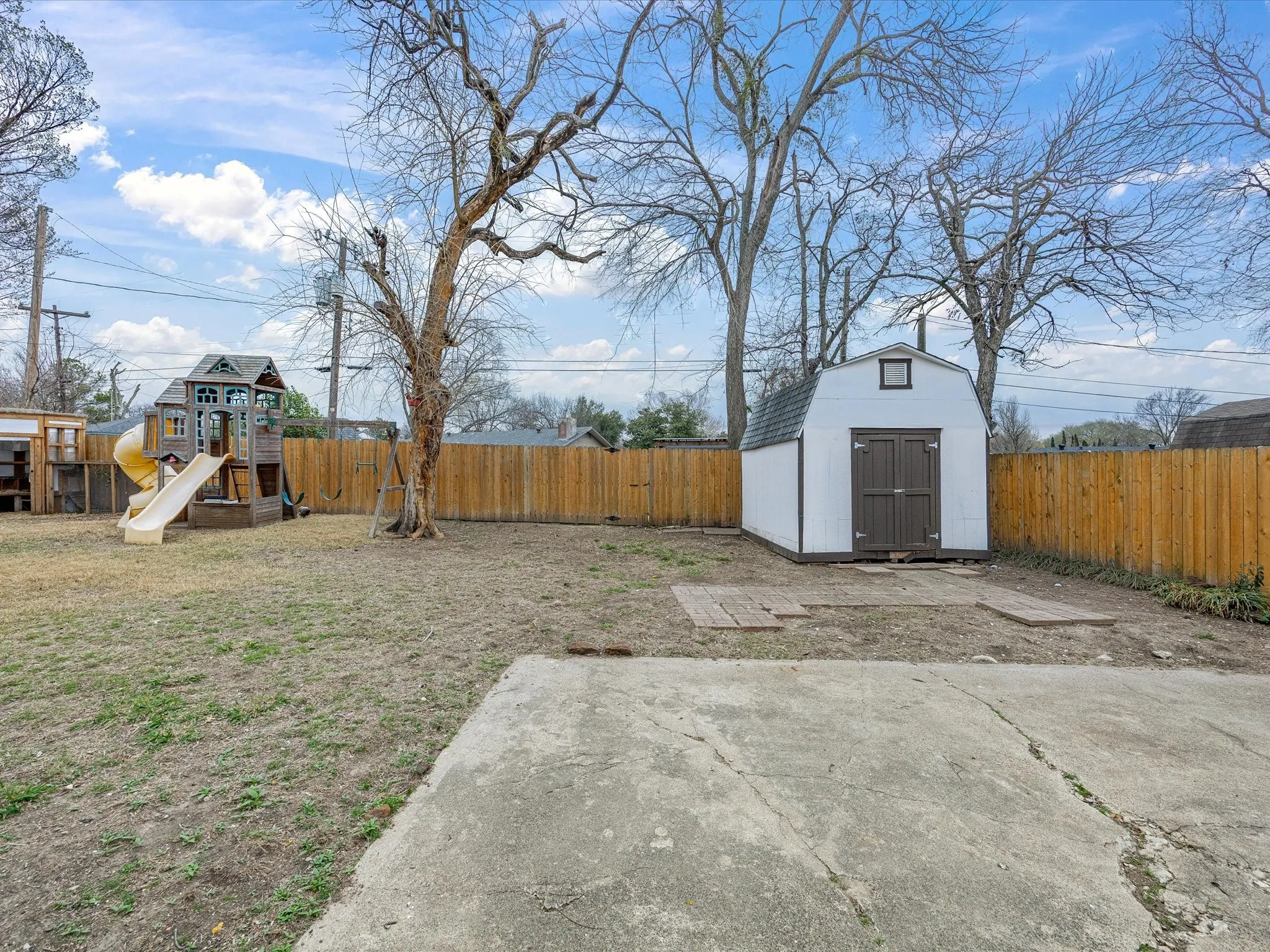 Fenced backyard featuring a shed and a playground
