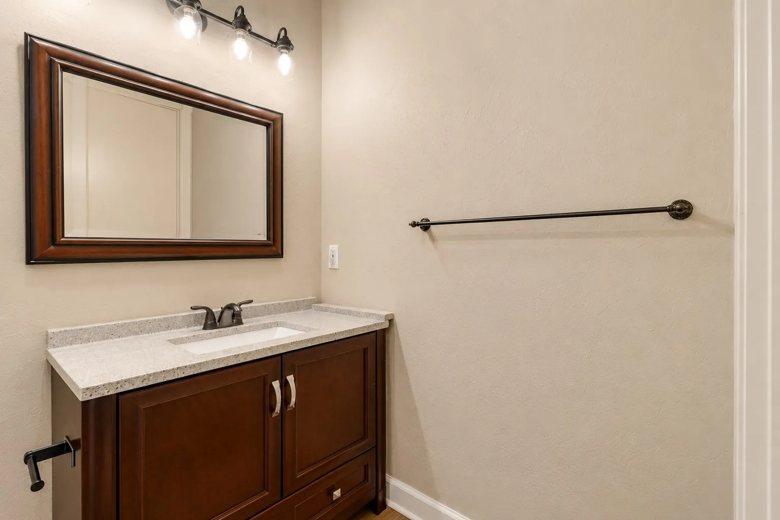 Bathroom vanity with a granite countertop, integrated sink, and dark wood-finish cabinetry