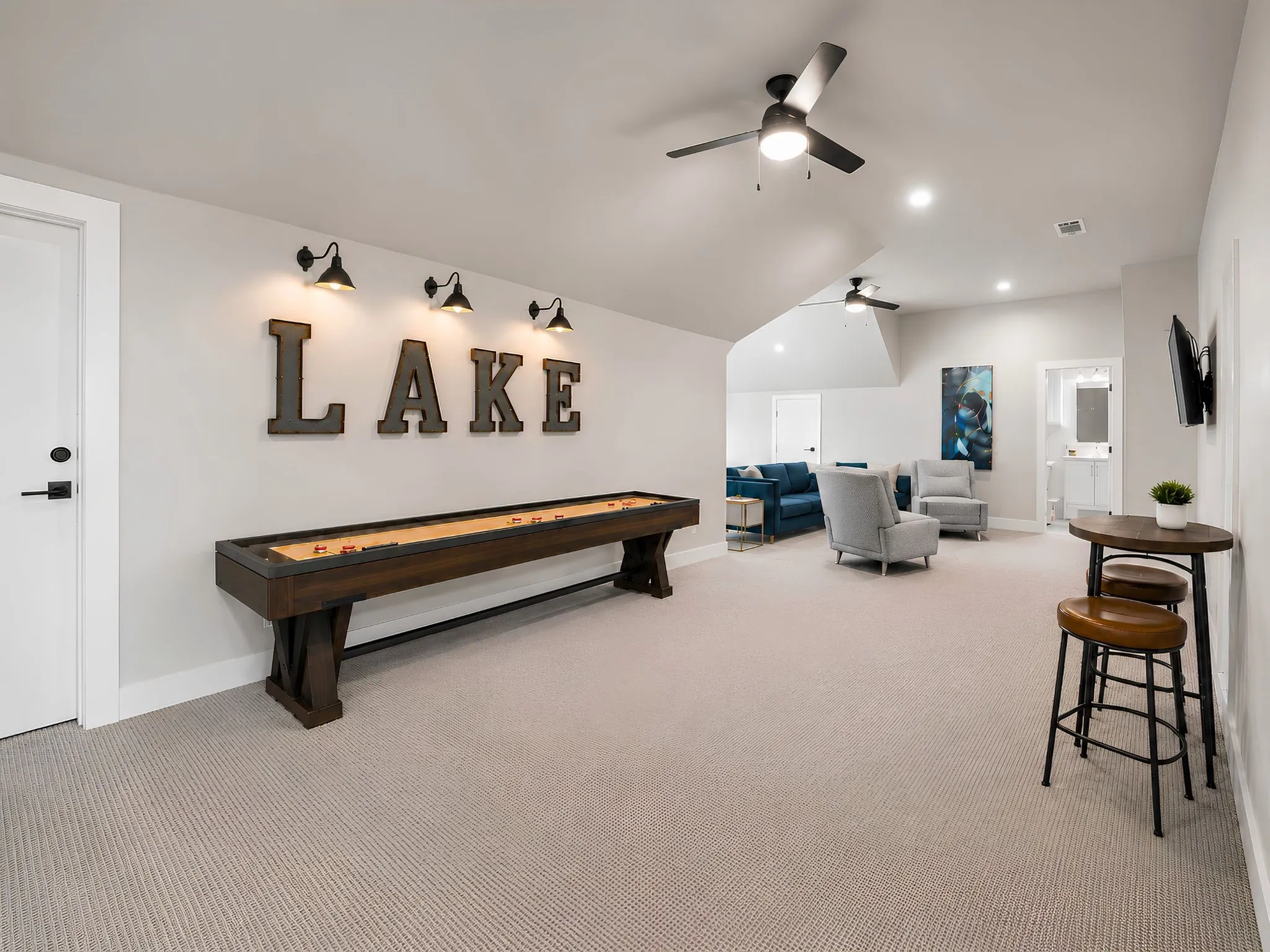 Spacious recreational room featuring carpeted flooring, sloped ceilings, recessed lighting, and ceiling fans