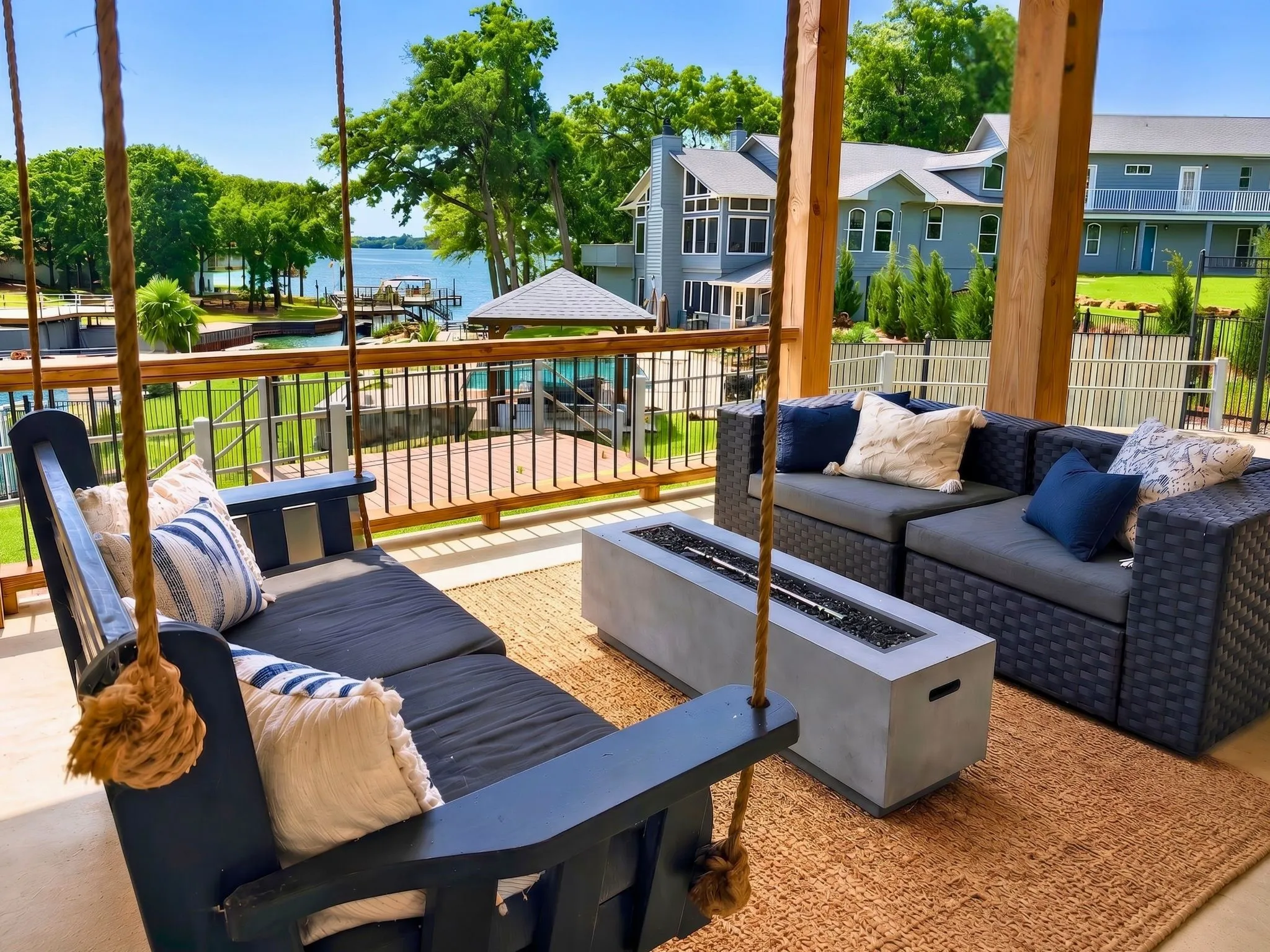 Covered outdoor living space featuring a porch swing, lounge seating, and a fire pit