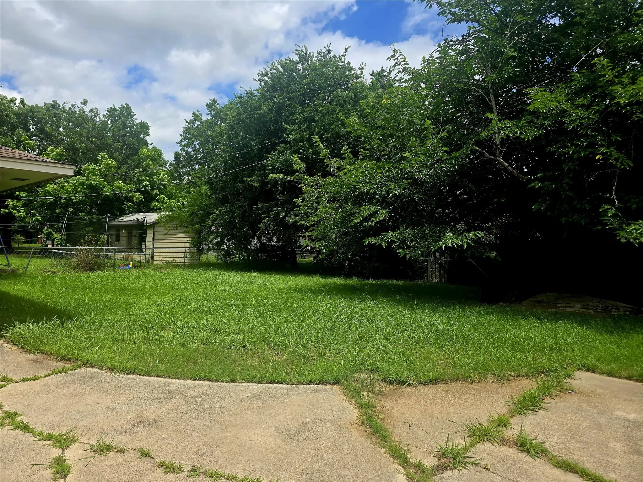 Expansive grassy yard with mature trees providing natural screening