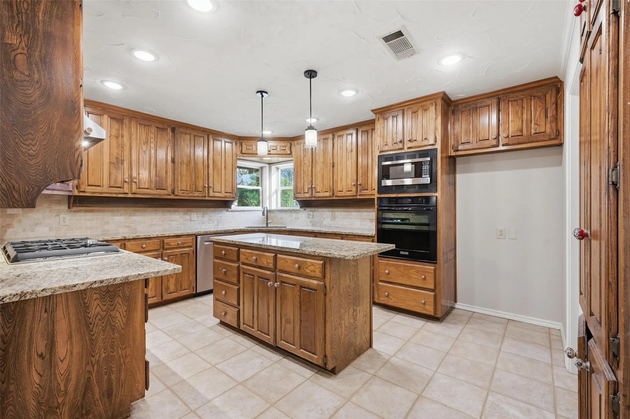 Kitchen featuring wood finish cabinetry, light stone countertops, a kitchen island, and stainless steel appliances