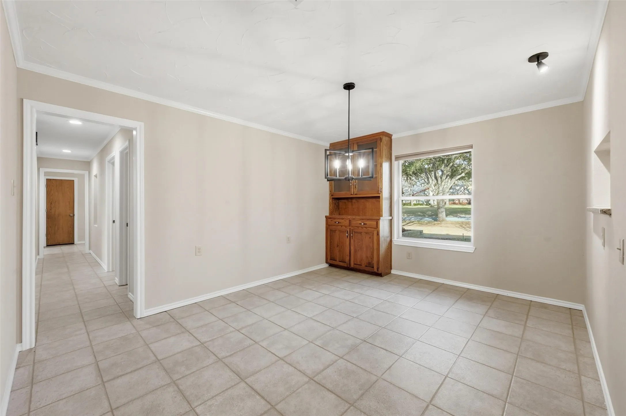 Unfurnished dining area with hanging lights, ornamental molding, and light tile patterned flooring