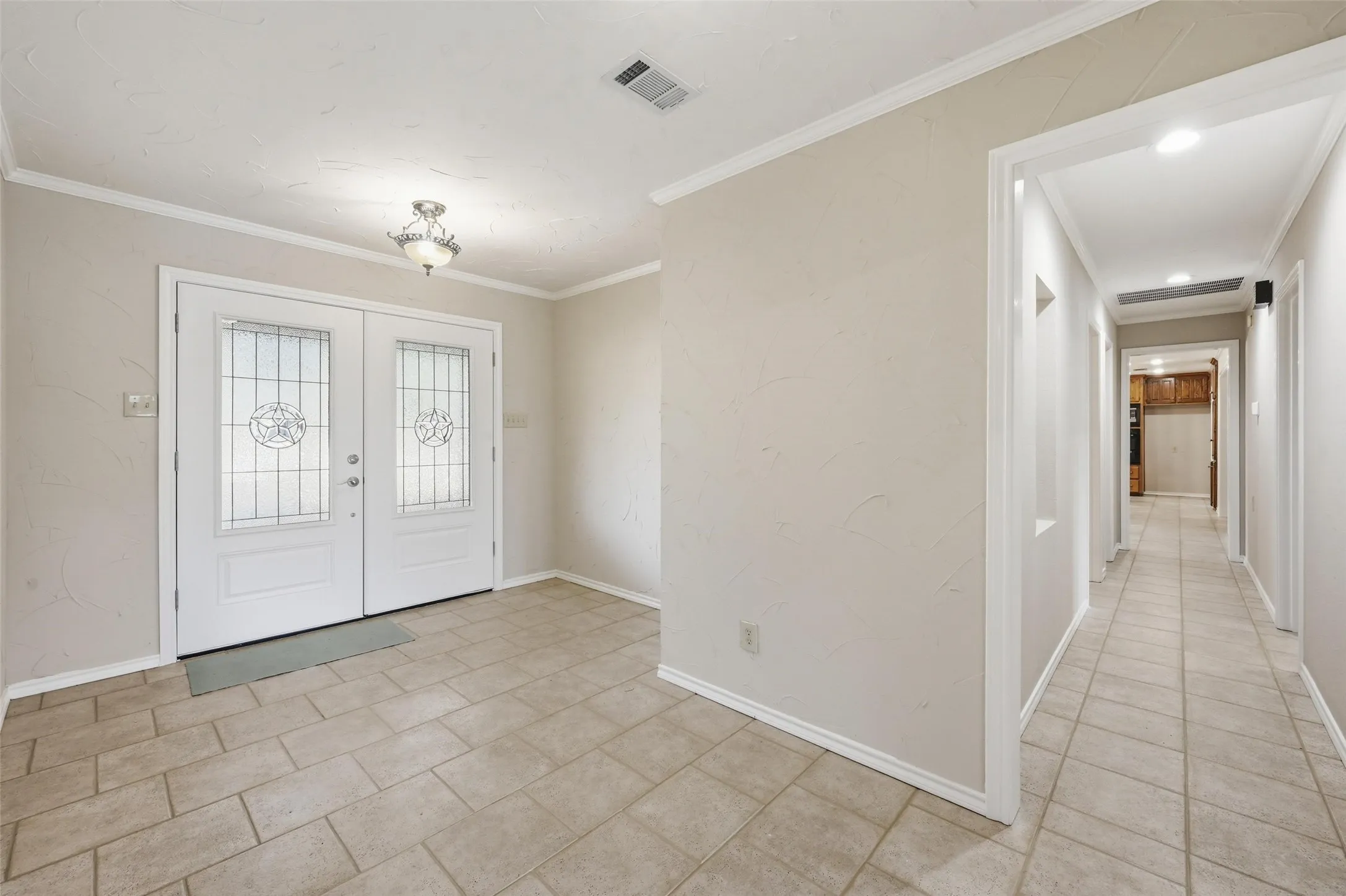 Entryway with crown molding, french doors, and light tile patterned flooring