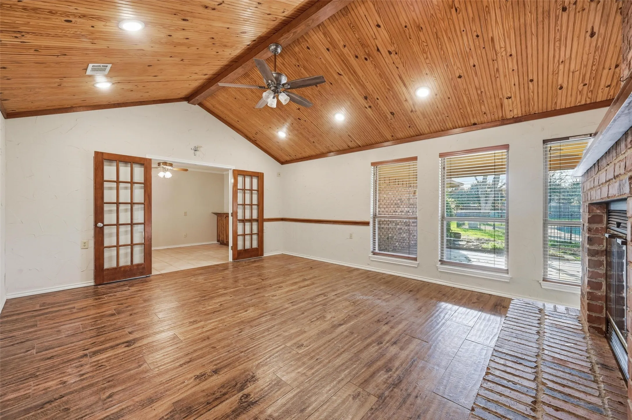 Unfurnished living room with a wooden ceiling with exposed beams, french doors, hardwood / wood-style flooring, and ceiling fan