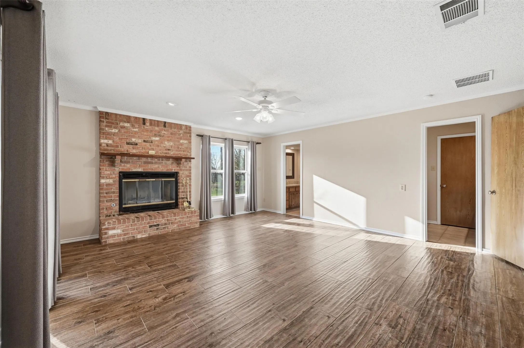 Master Bedroom featuring ceiling fan, dark wood-type flooring, a fireplace, crown molding, and a textured ceiling