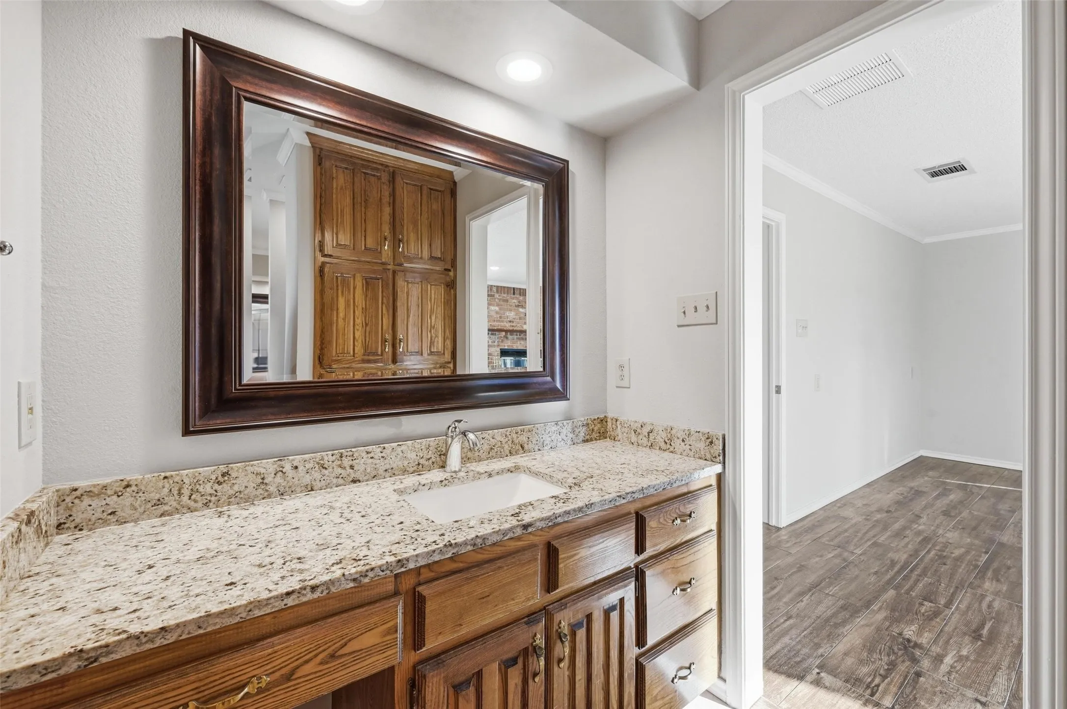 Bathroom featuring vanity, wood finished floors, and crown molding