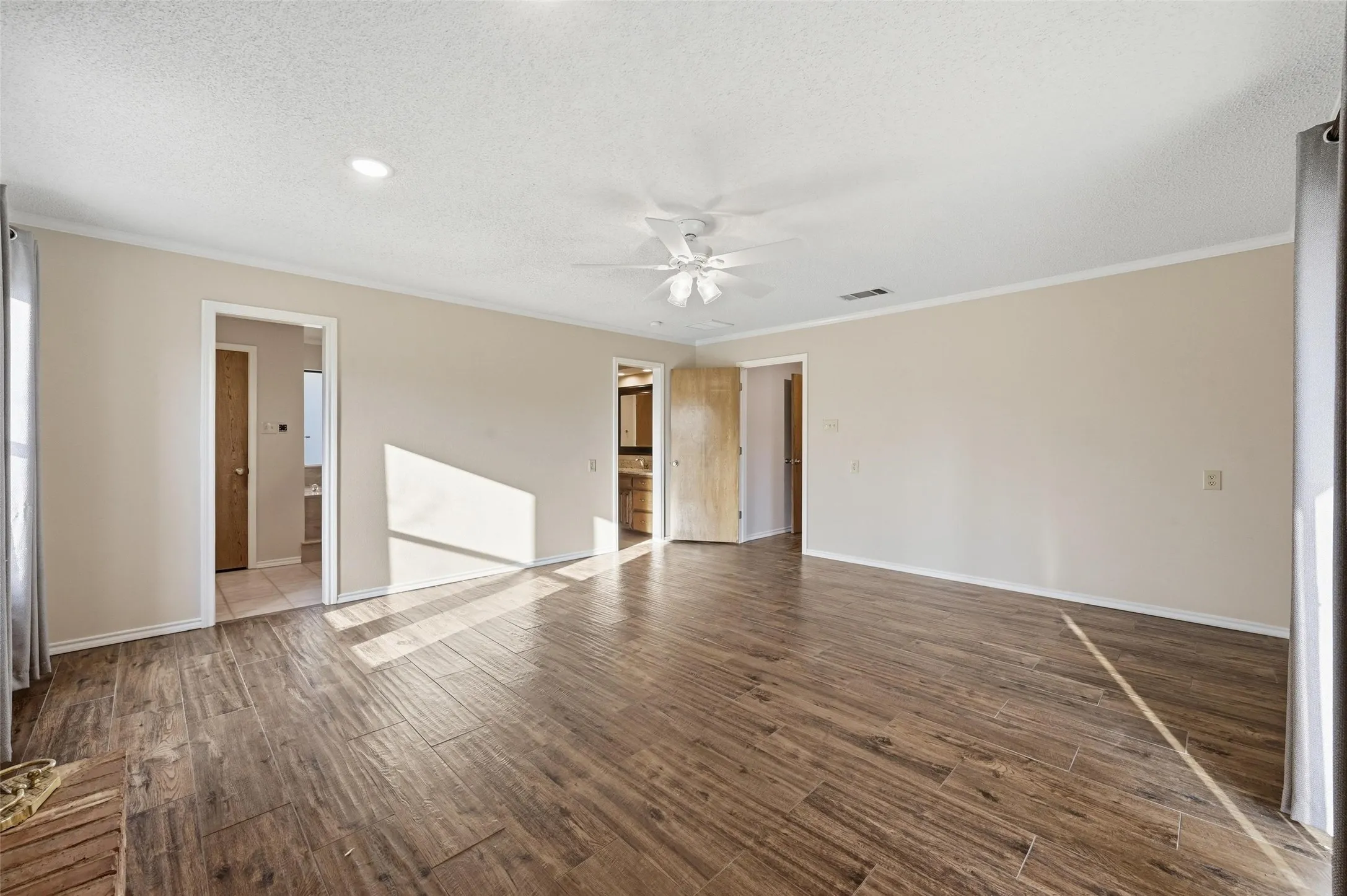 Master bedroom featuring ceiling fan, dark wood-type flooring, a textured ceiling, and crown molding