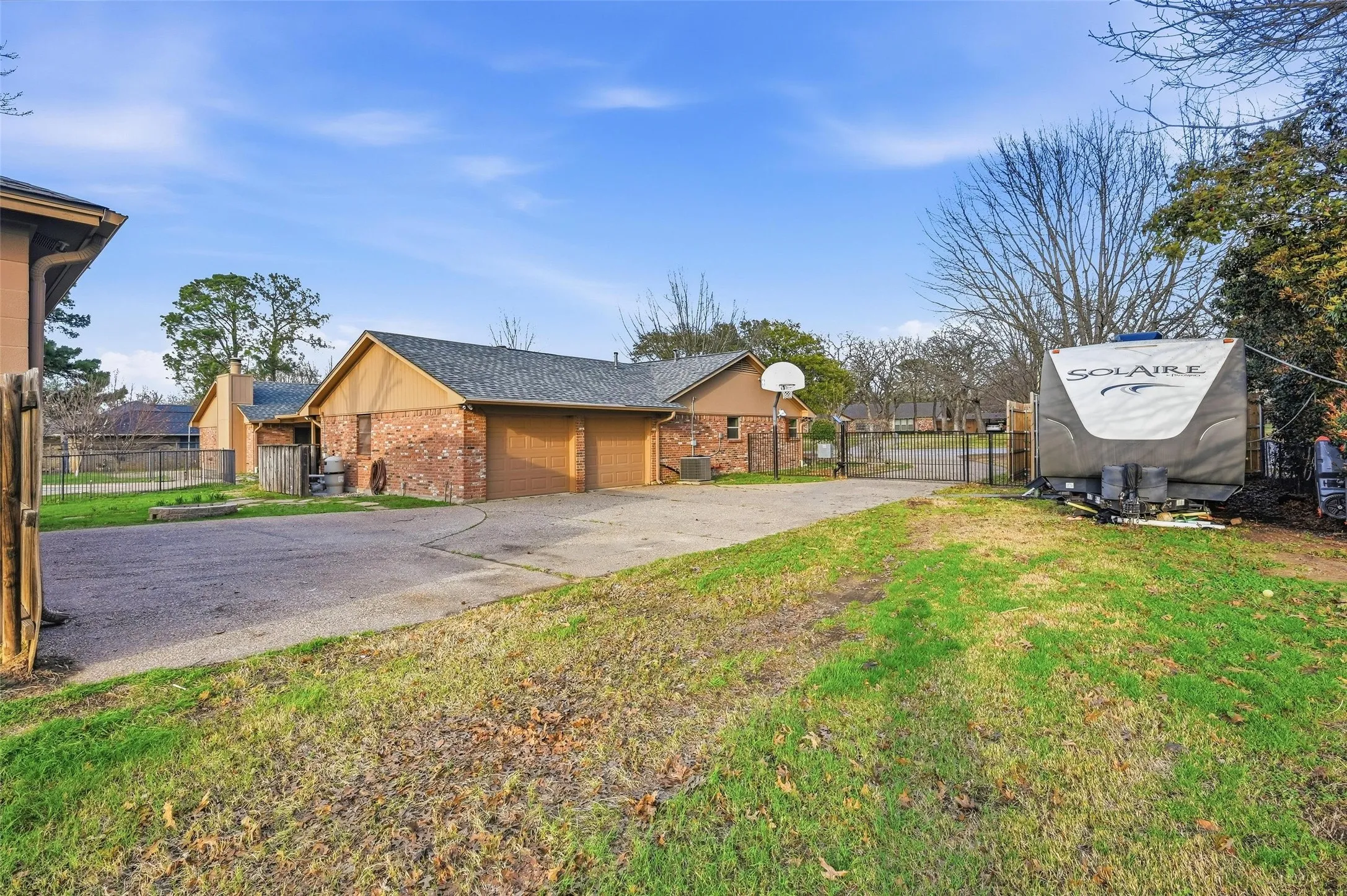View of home's exterior featuring a gate, brick siding, concrete driveway, a garage, and a shingled roof