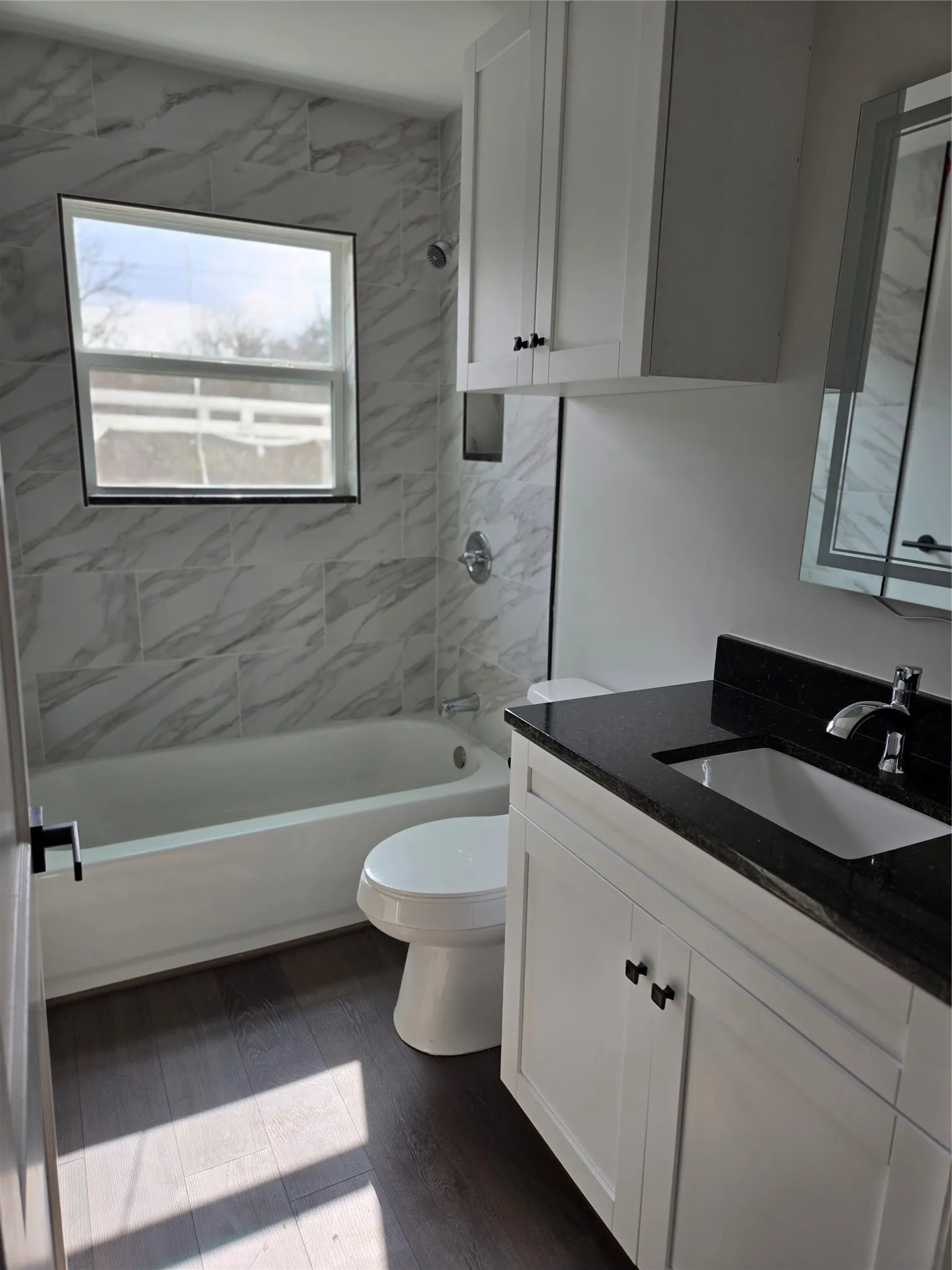 Bathroom with vanity, dark wood-style floors, and shower / bath combination