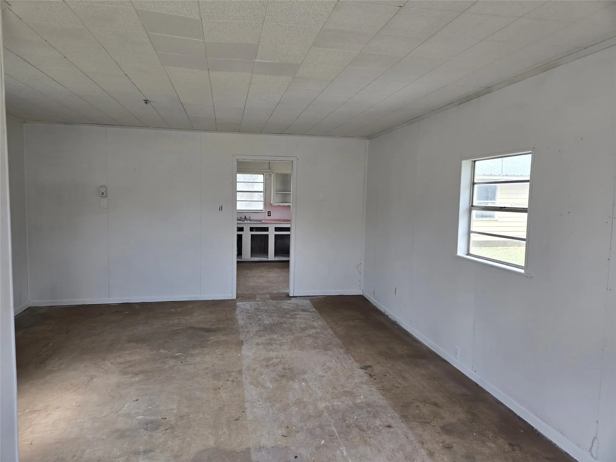 Unfurnished room featuring unfinished concrete floors and baseboards
