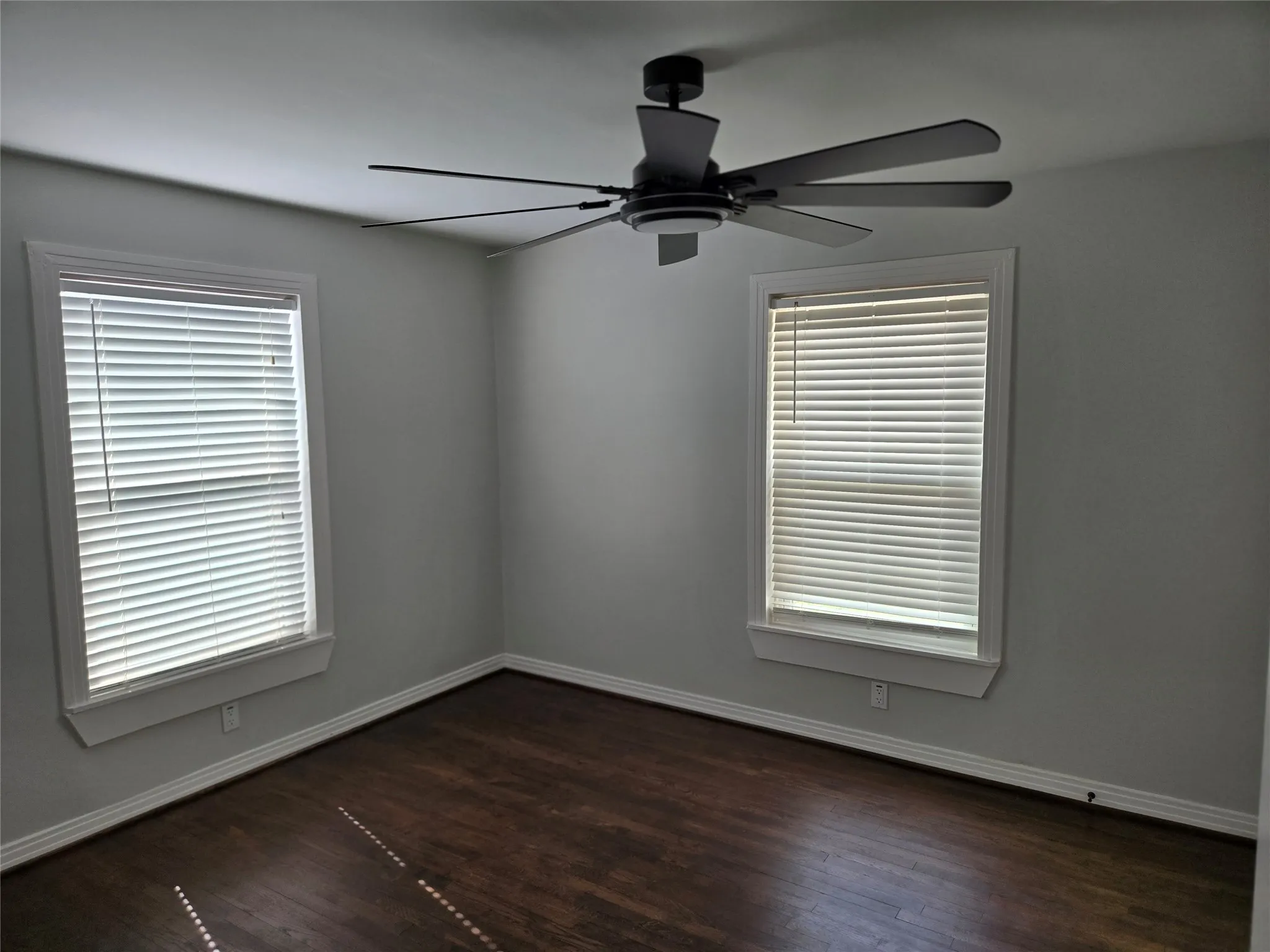 Spare room featuring ceiling fan and dark wood-style flooring