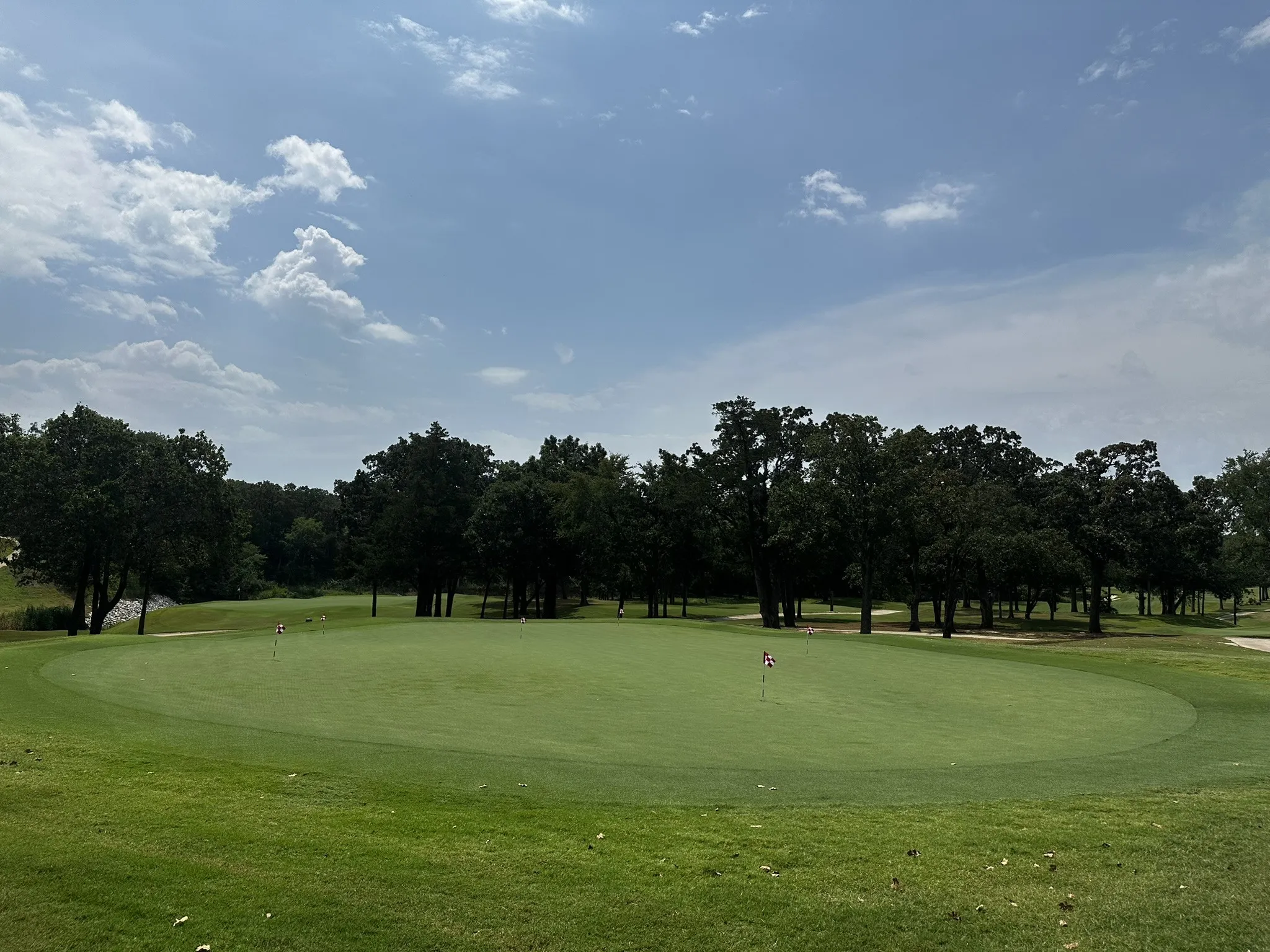 View of property's community featuring golf course view, a putting green, and view of scattered trees