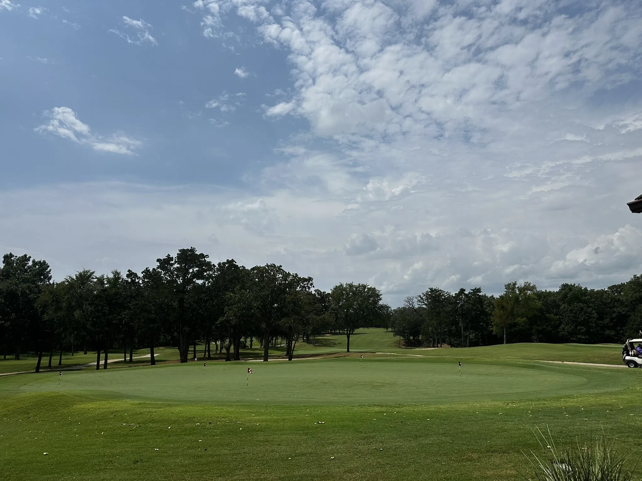 View of property's community with golf course view, an area to practice putting, and view of scattered trees