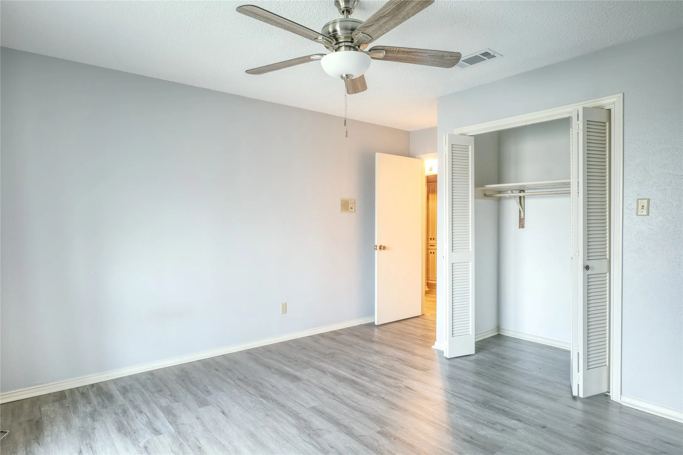Unfurnished bedroom with a closet, wood finished floors, and a ceiling fan