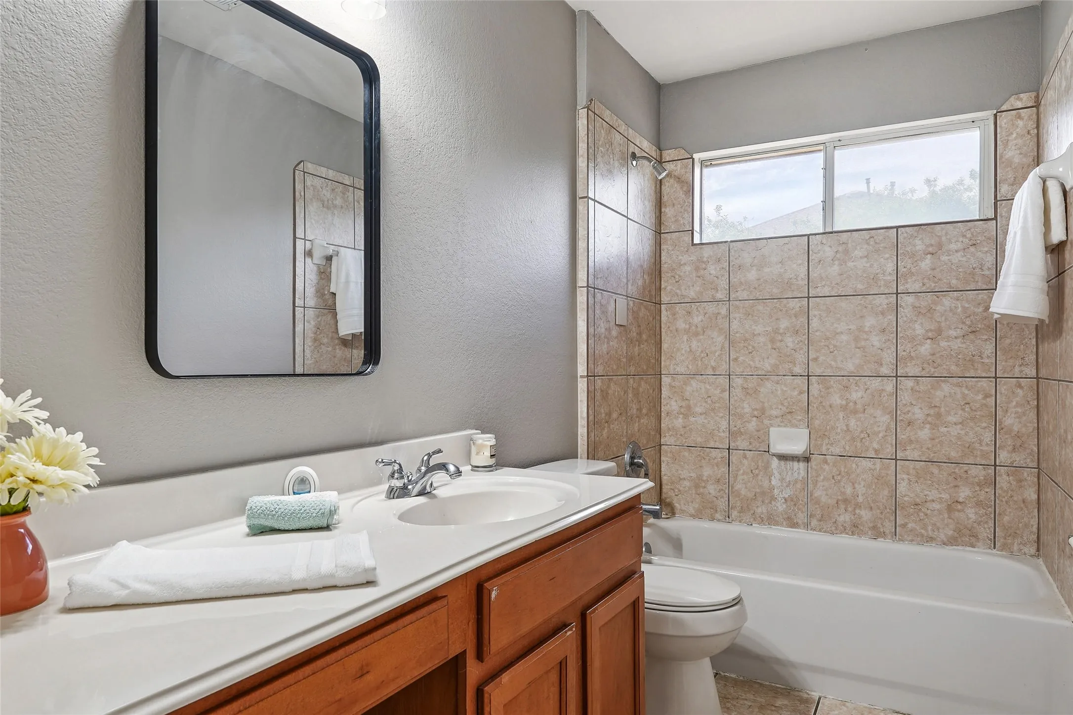 Full bathroom featuring vanity, a textured wall, and washtub / shower combination