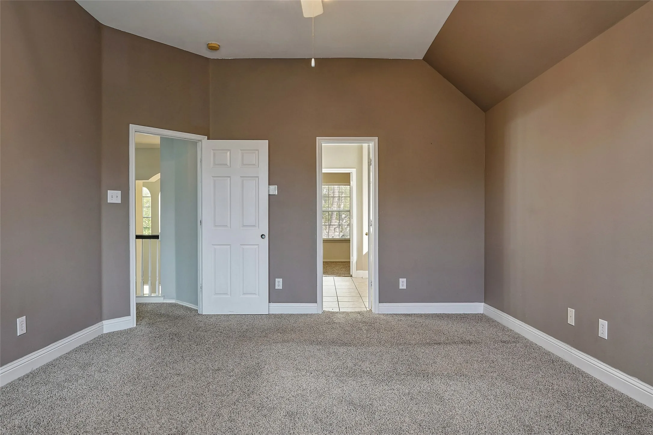 Unfurnished bedroom with light carpet, connected bathroom, and lofted ceiling