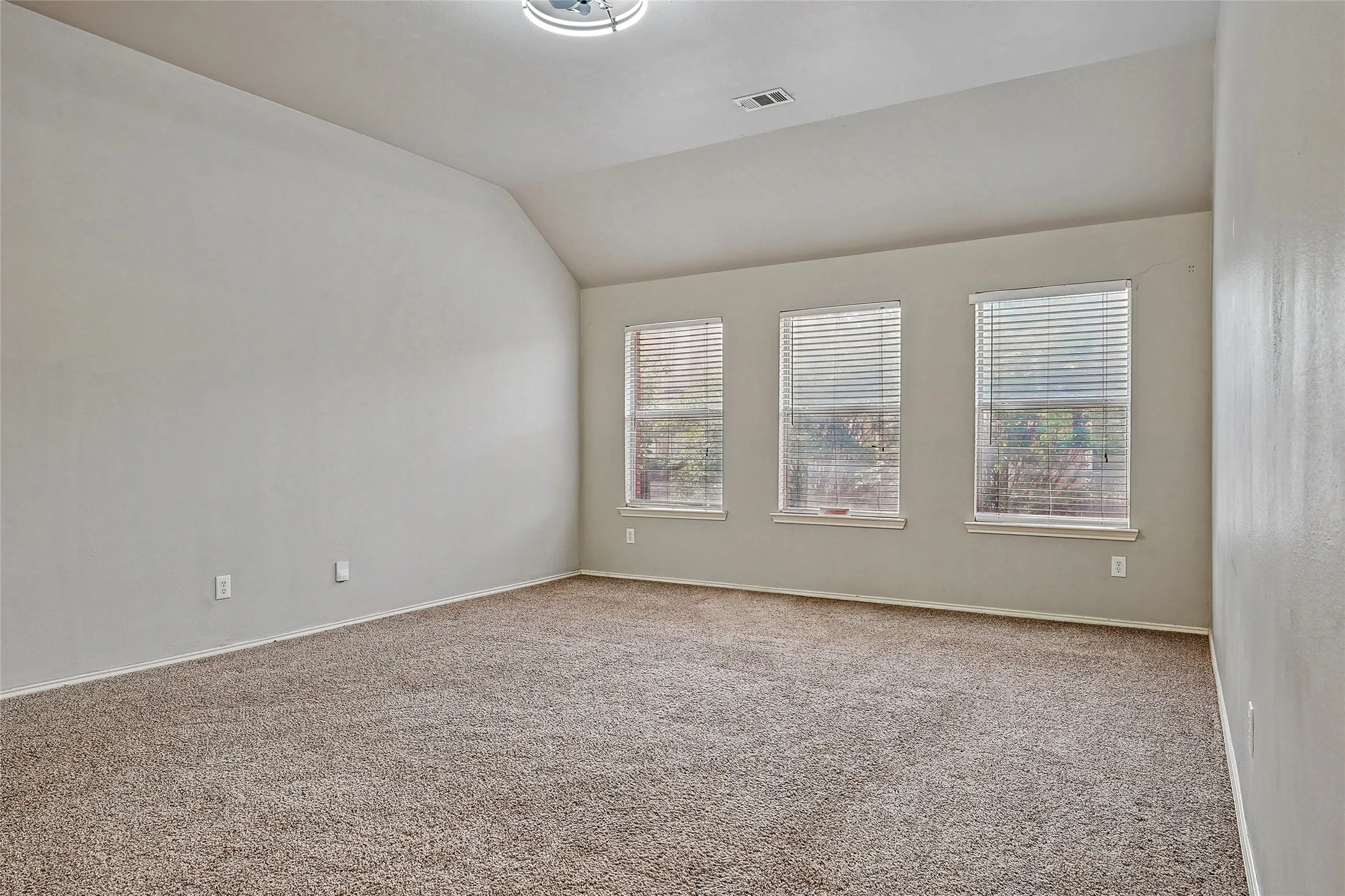 Carpeted empty room with lofted ceiling and baseboards