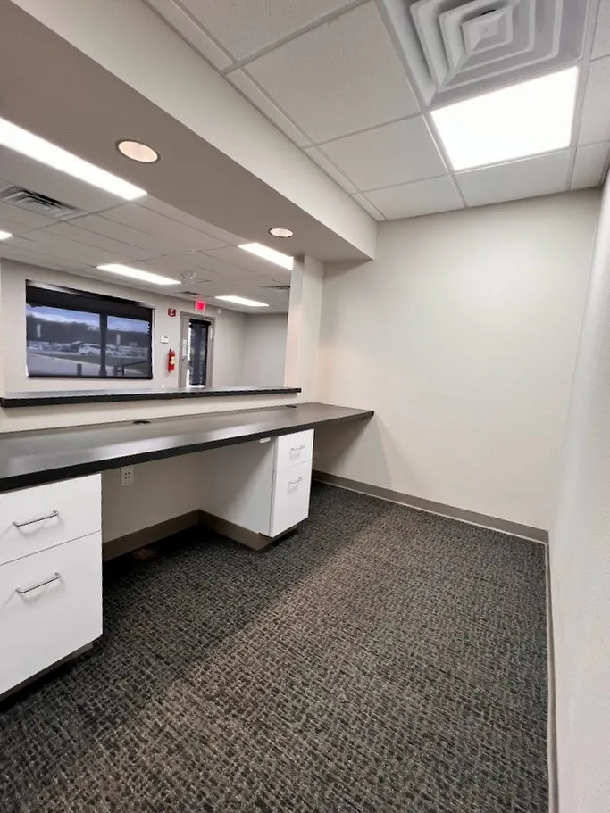Unfurnished office with a drop ceiling and built in desk