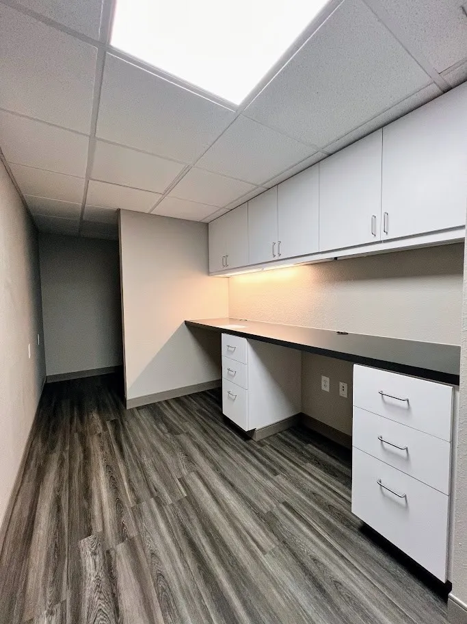Unfurnished office featuring a paneled ceiling, built in desk, and dark wood finished floors