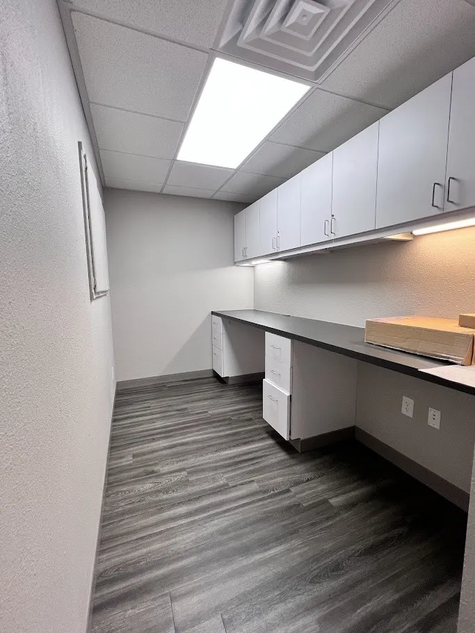 Unfurnished office with built in desk, a textured wall, a paneled ceiling, and dark wood-type flooring