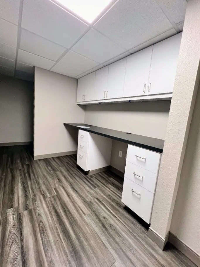 Unfurnished office with a paneled ceiling, built in desk, and dark wood-style flooring