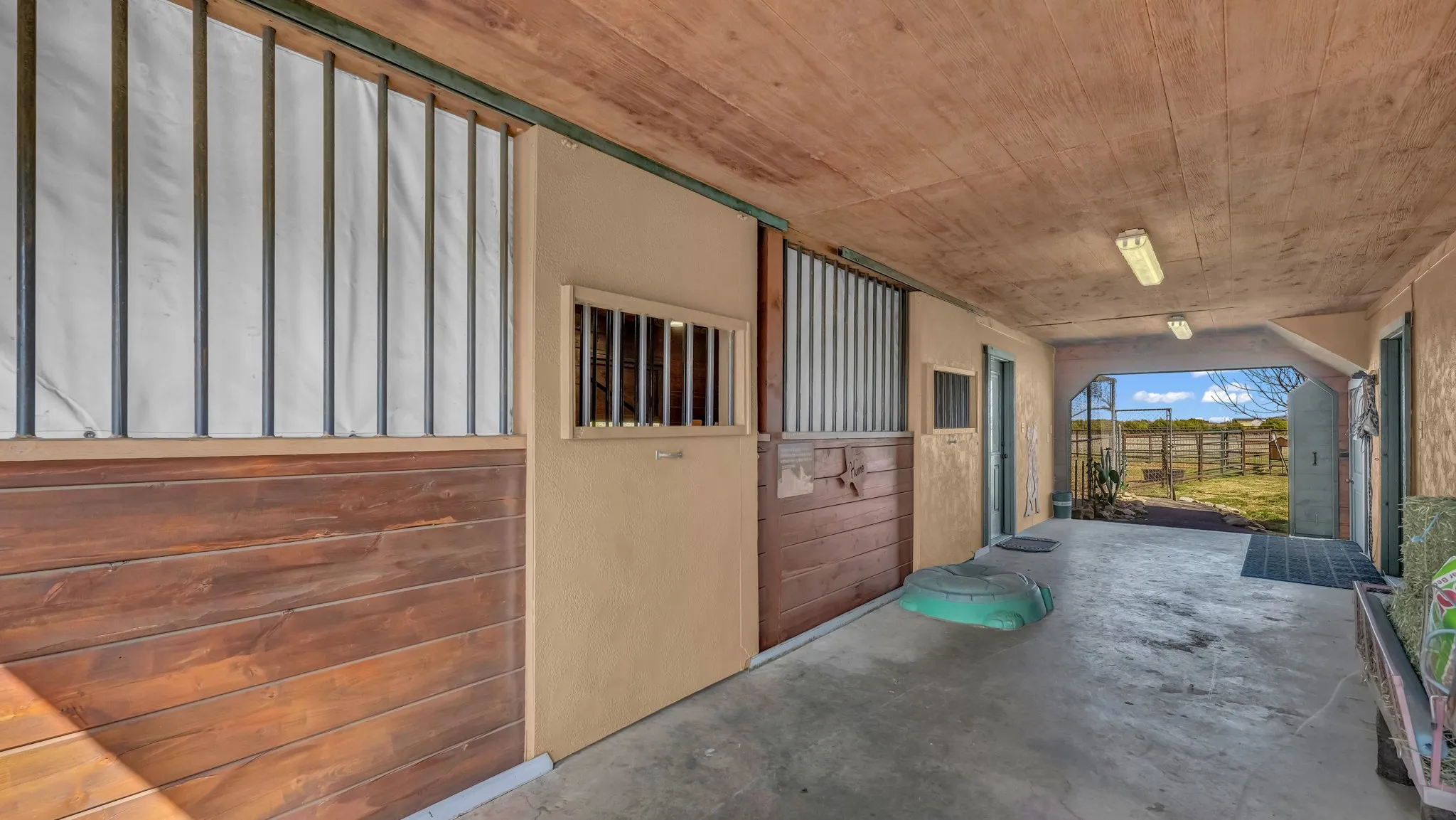 Barn has two functioning stalls, tack room on the left and living quarters on the right. This breezeway leads to the chicken coop and open pastures behind the house.