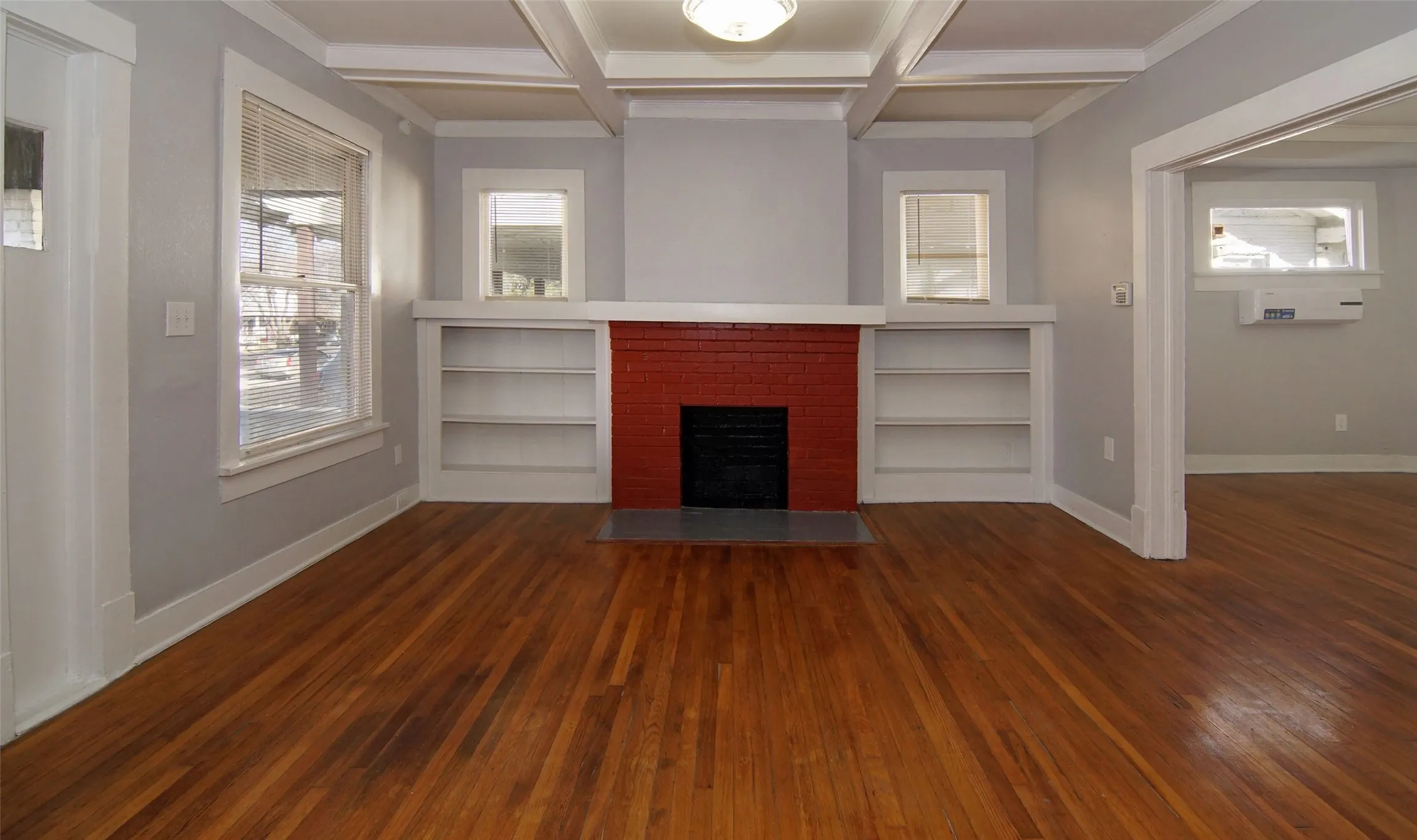 Built in shelves, Coffer ceilings, natural wood floors, decorative fireplace for an antique gas heater insert