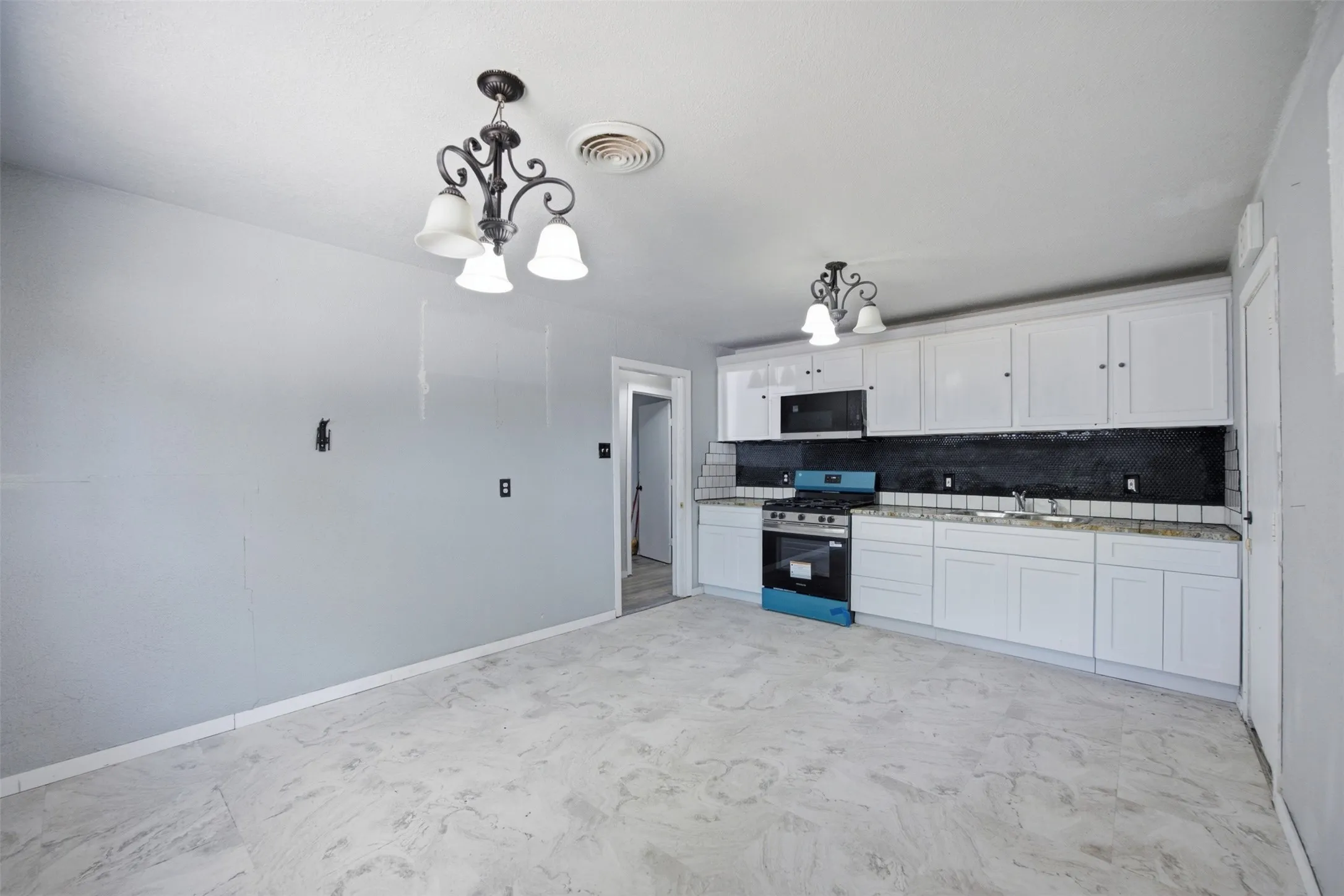 Kitchen featuring white shaker cabinetry, light-toned countertops, a stainless steel range, and a tile backsplash