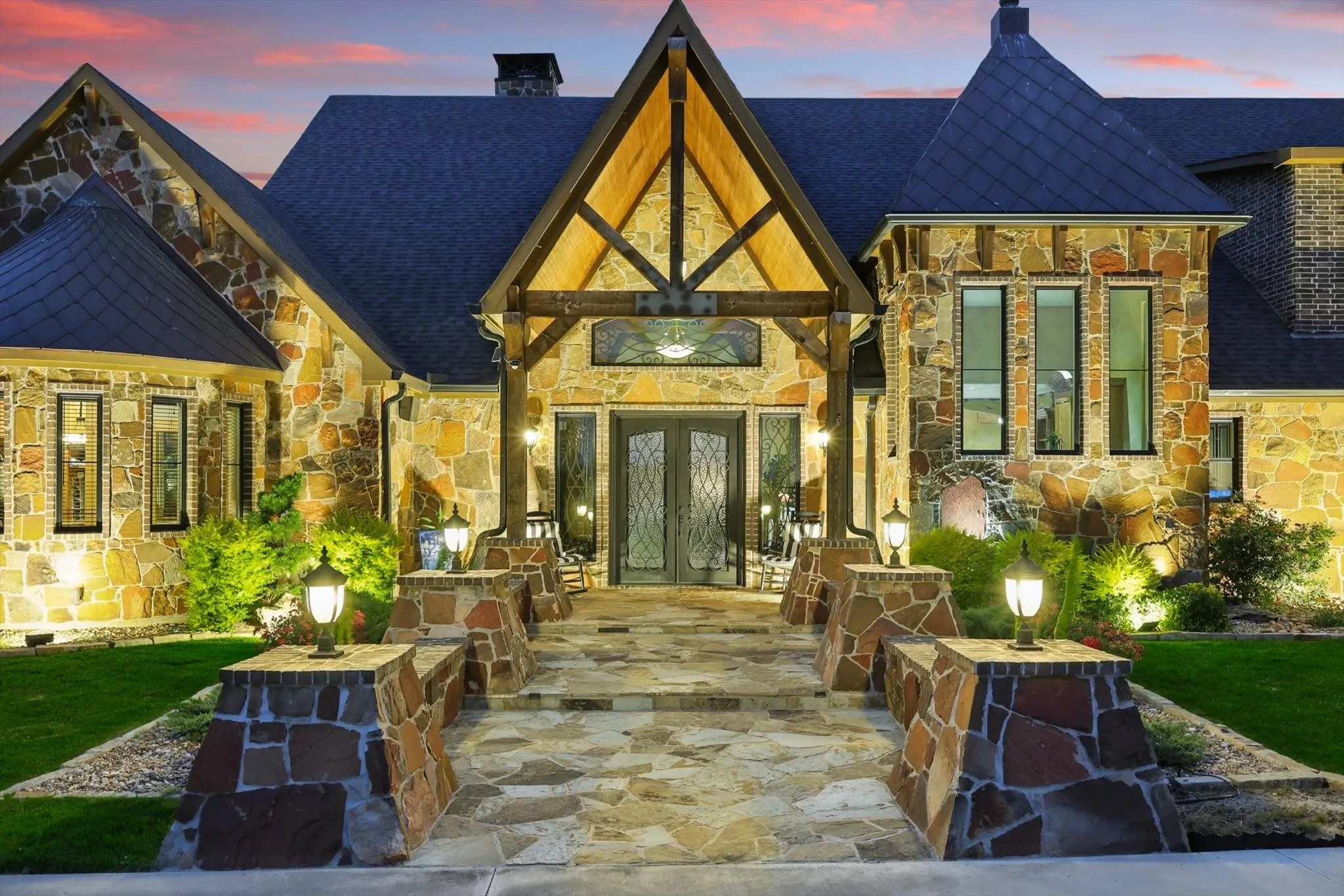 Back of property at dusk with stone siding, a chimney, french doors, and a shingled roof
