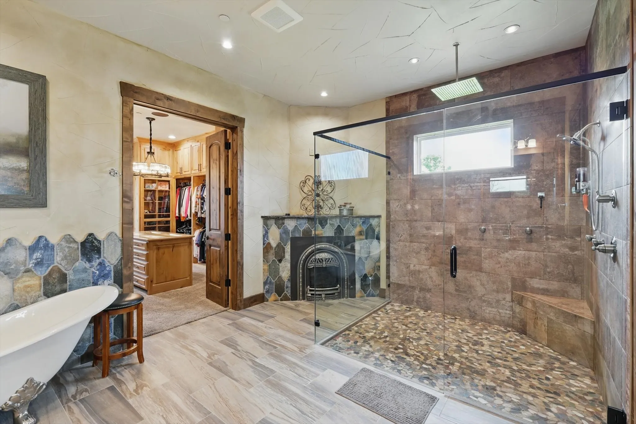 Bathroom featuring a walk in closet, a freestanding tub, a fireplace, a stall shower, and recessed lighting