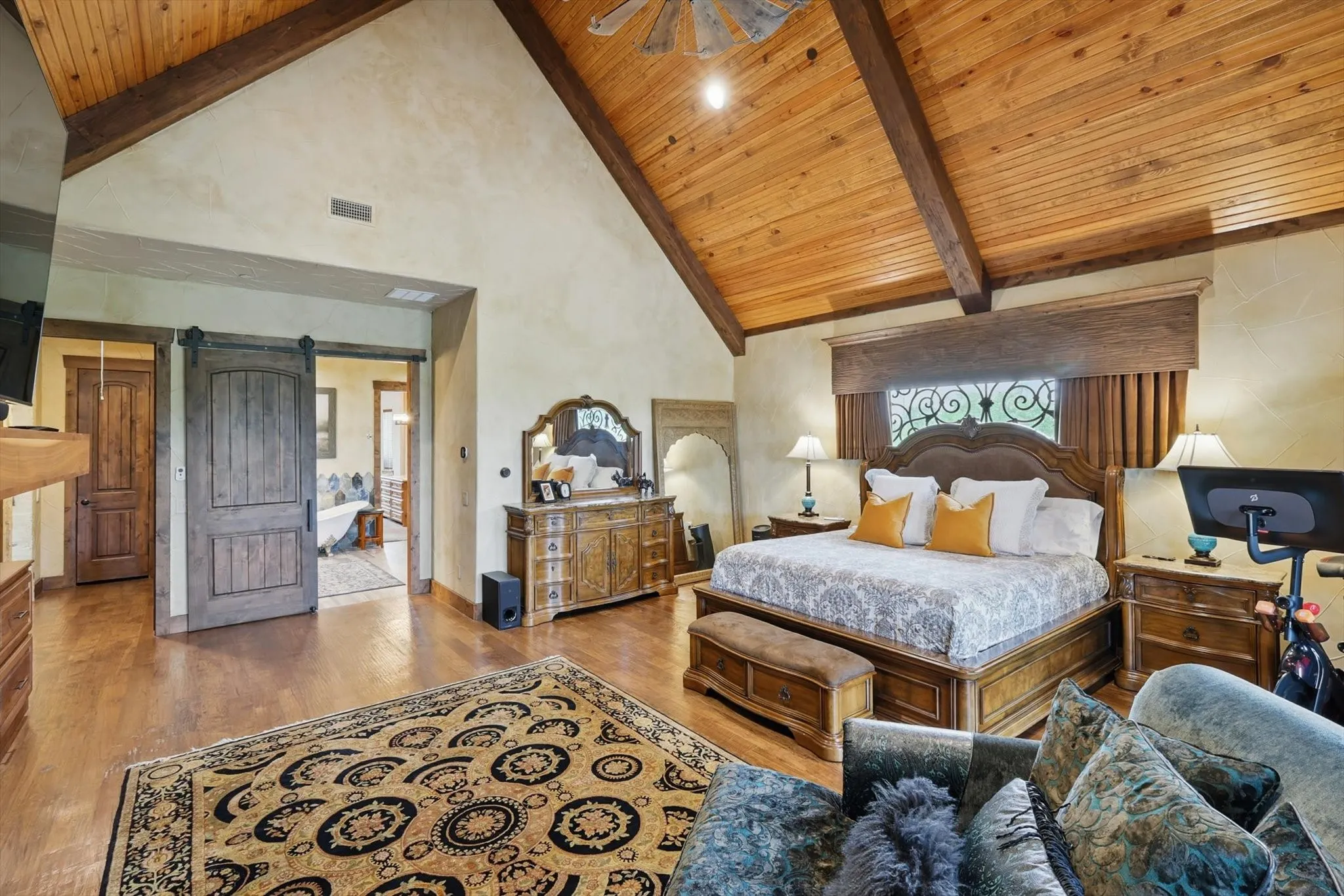 Bedroom featuring a barn door, wood finished floors, and a high wood beamed ceiling
