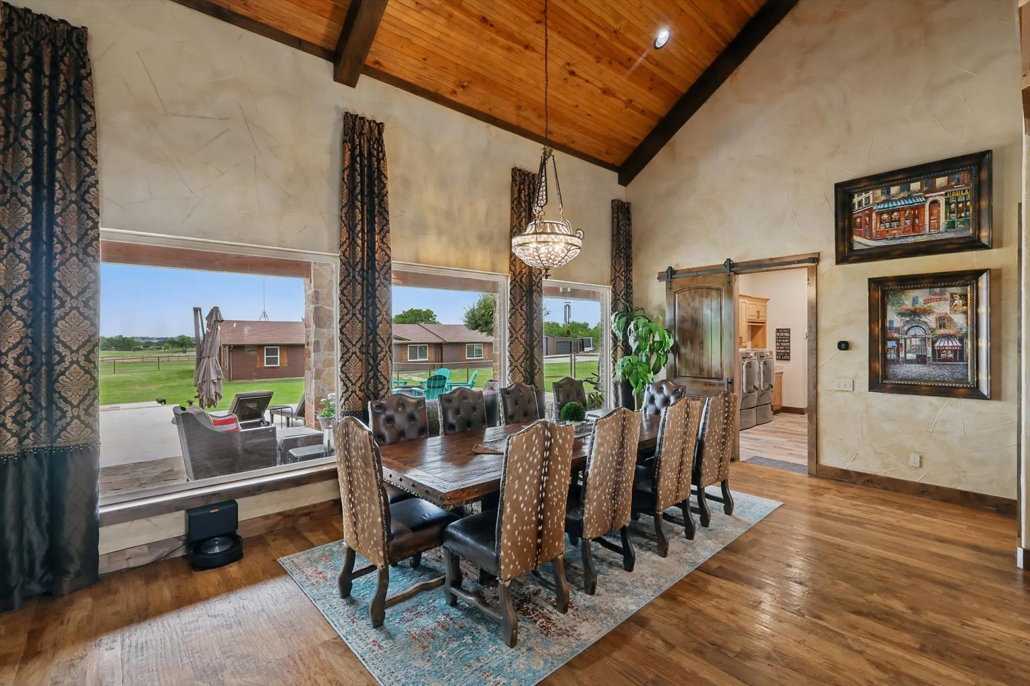 Dining space with a barn door, hardwood / wood-style floors, a vaulted wooden ceiling, and suspended lighting