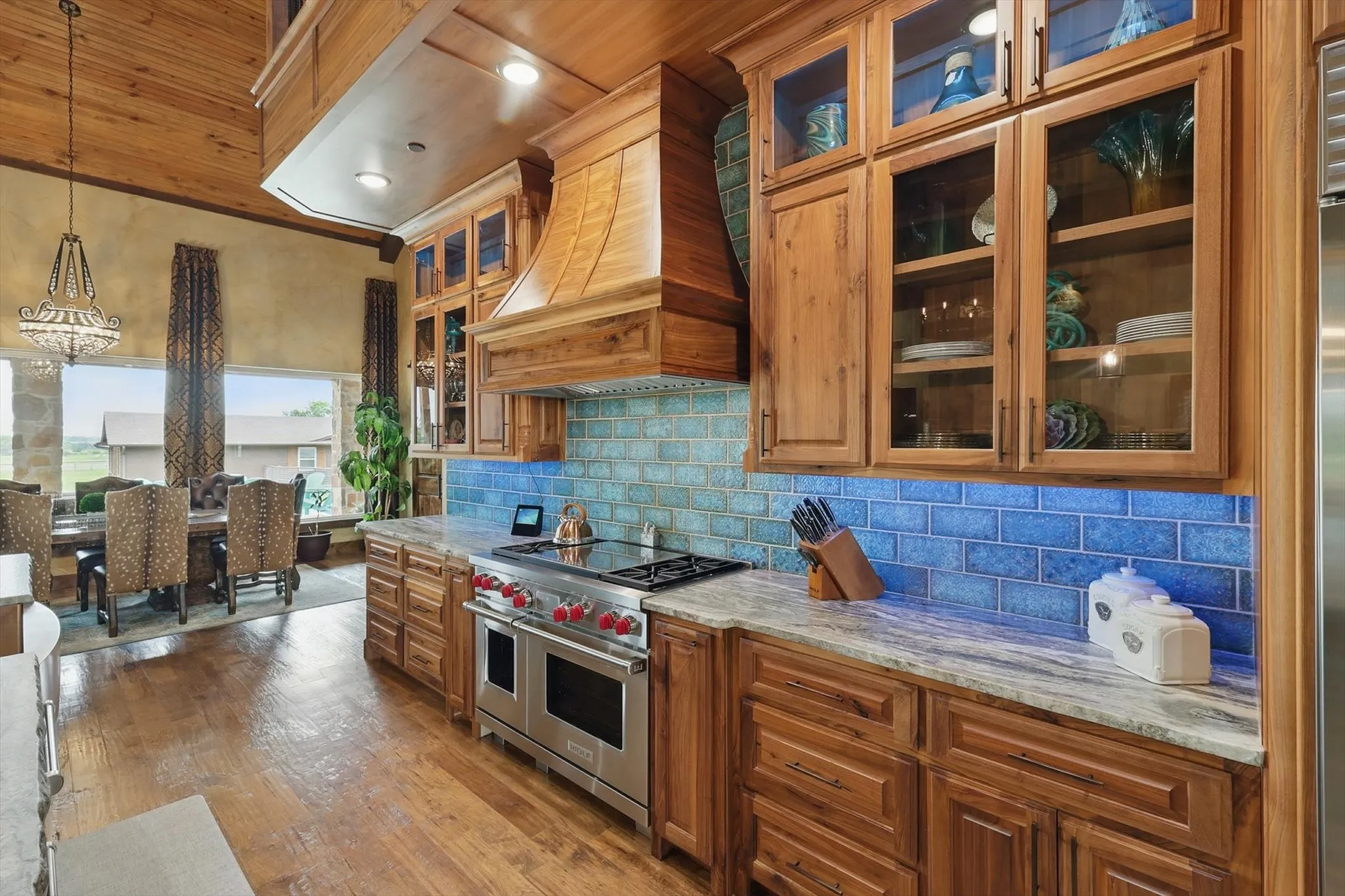 Kitchen with glass insert cabinets, light stone counters, wood finish cabinetry, range with two ovens, and wooden ceiling