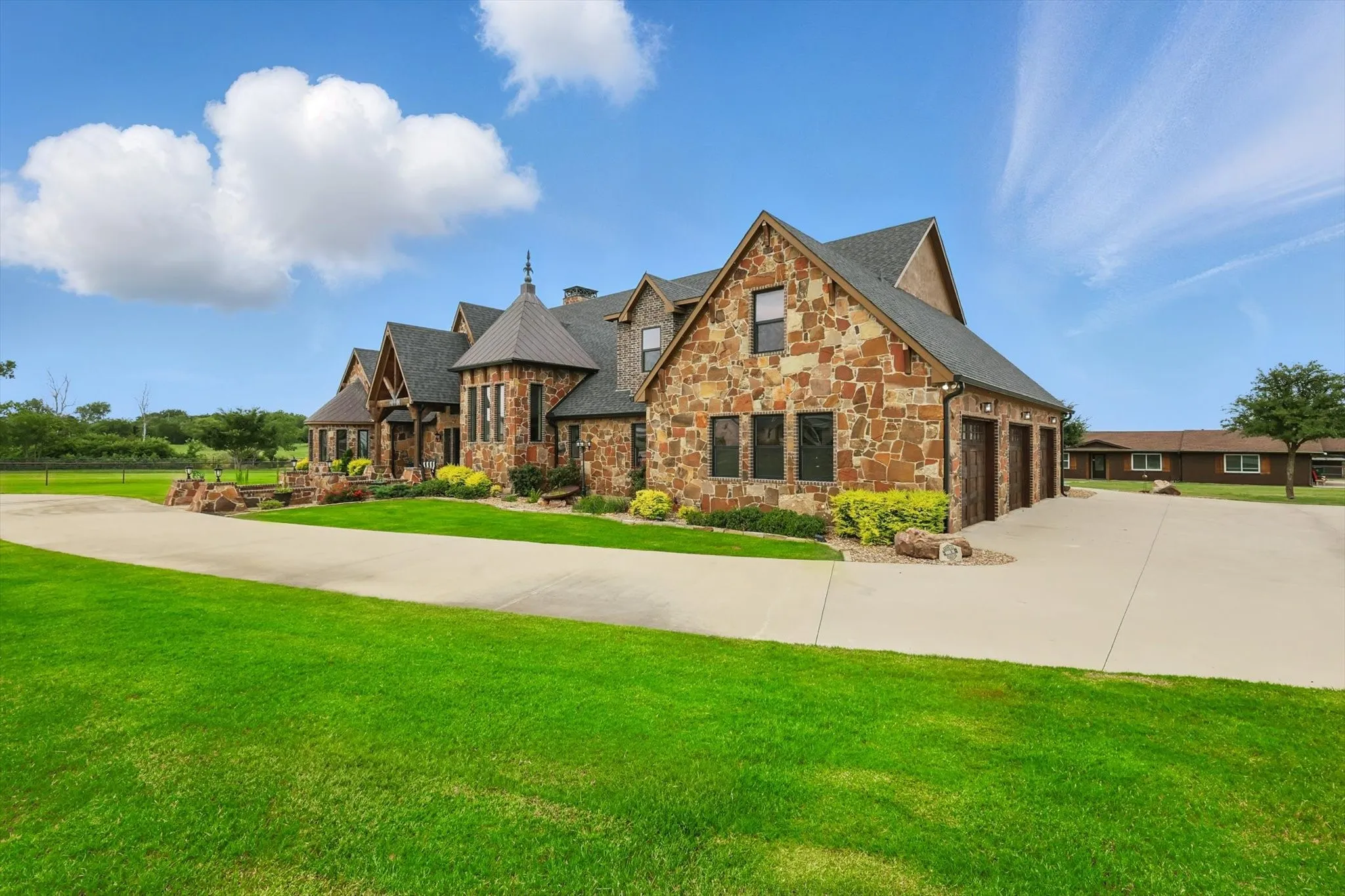 View of front facade with stone siding, a front yard, driveway, and an attached garage