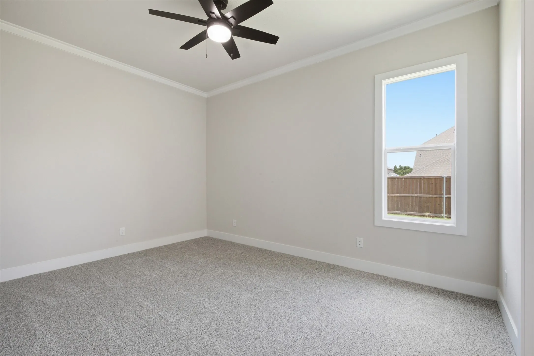 Spacious room featuring neutral carpeting, a single window, and a ceiling fan with integrated lighting