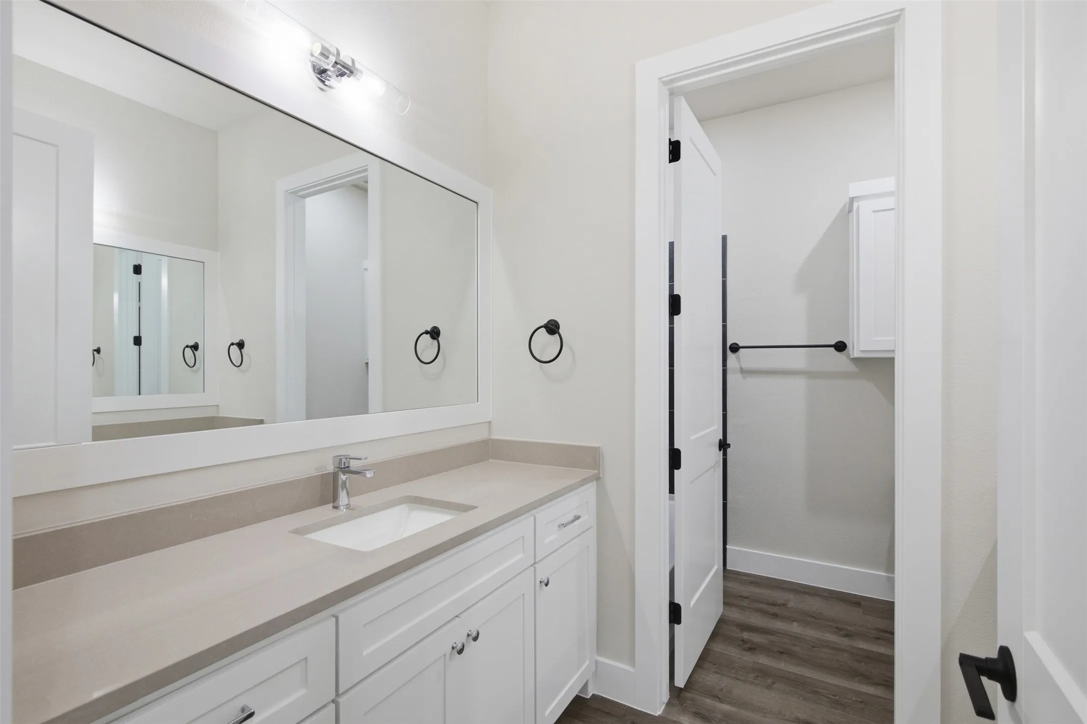 Bathroom vanity featuring a single undermount sink, a chrome faucet, and a large framed mirror with overhead lighting