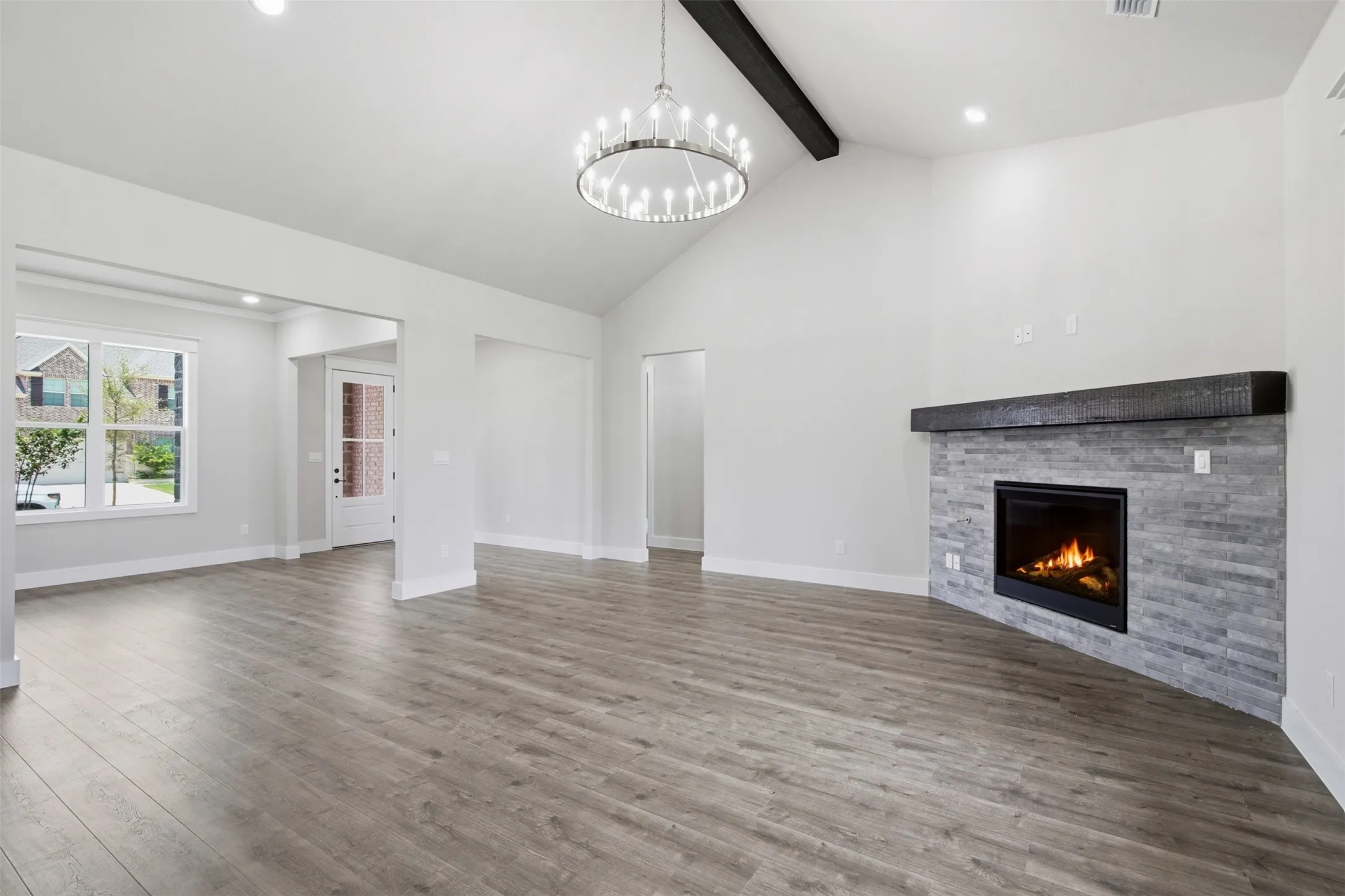 Spacious living area featuring a vaulted ceiling, a modern chandelier, and recessed lighting