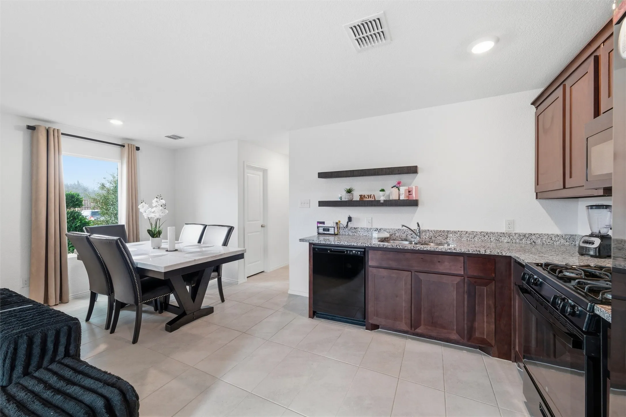 Kitchen with black appliances, light stone countertops, open shelves, recessed lighting, and dark wood finish cabinets